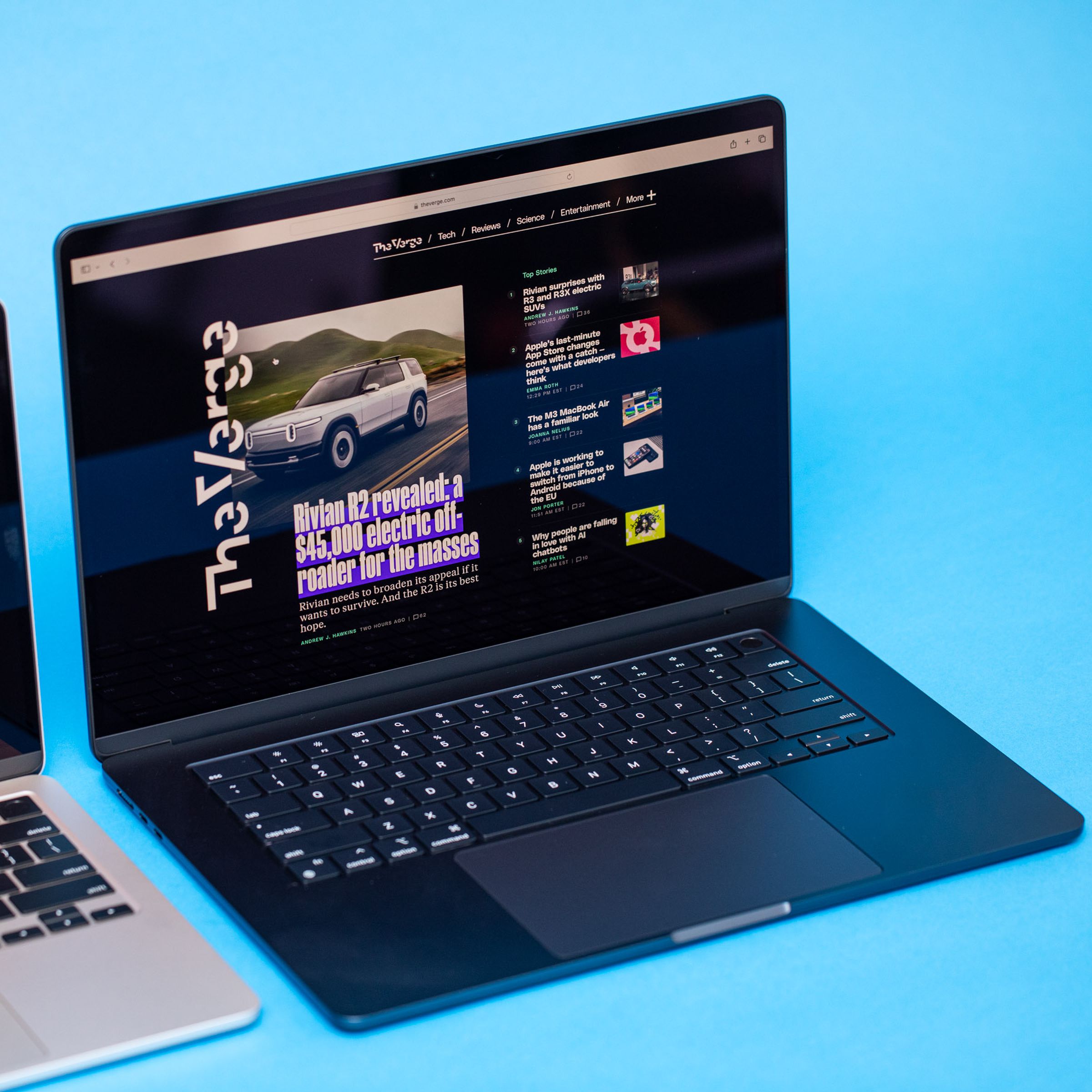 An angled photo of two open and powered on laptops against a light blue background.