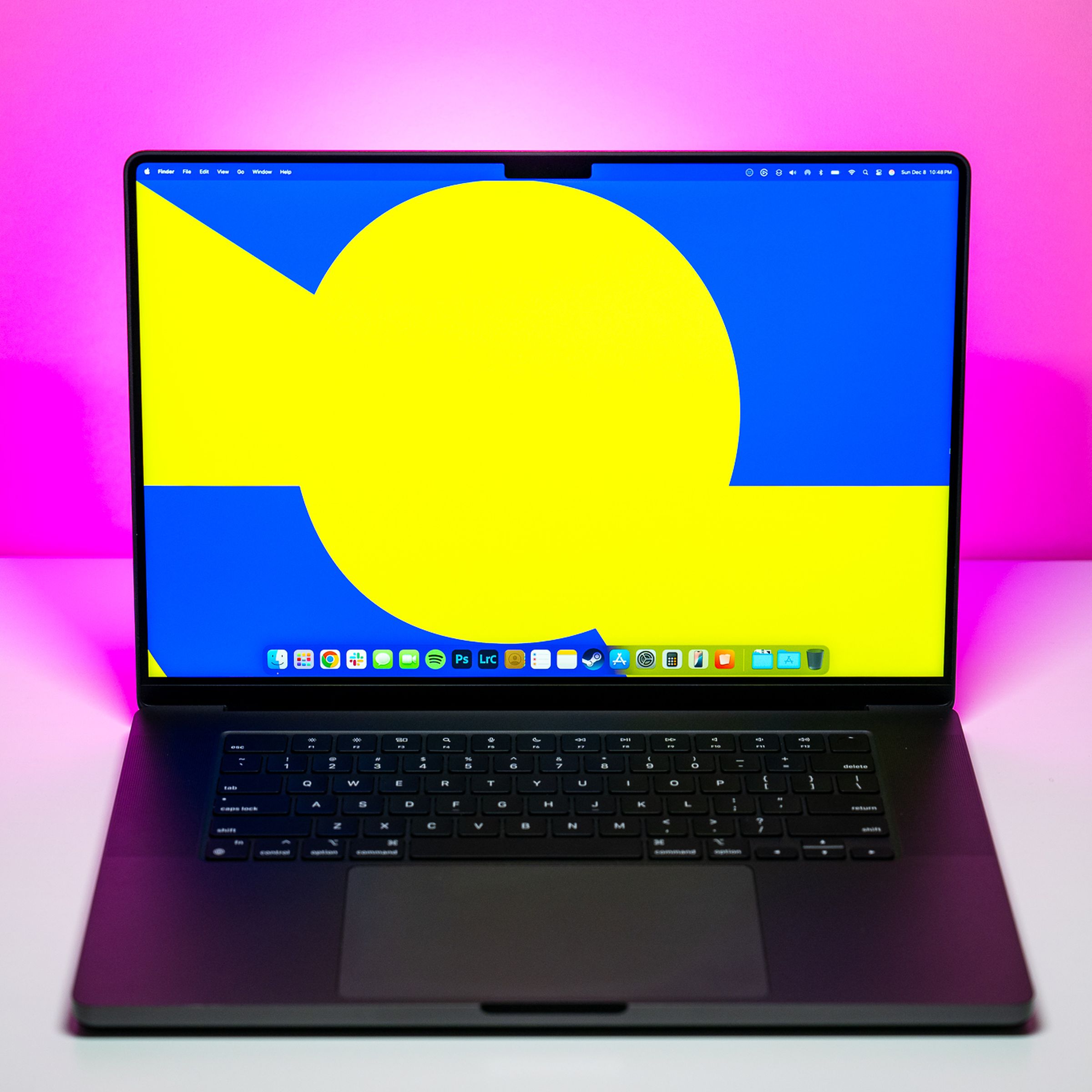 The 16-inch MacBook Pro with M4 Max chip on a white table with pink background.