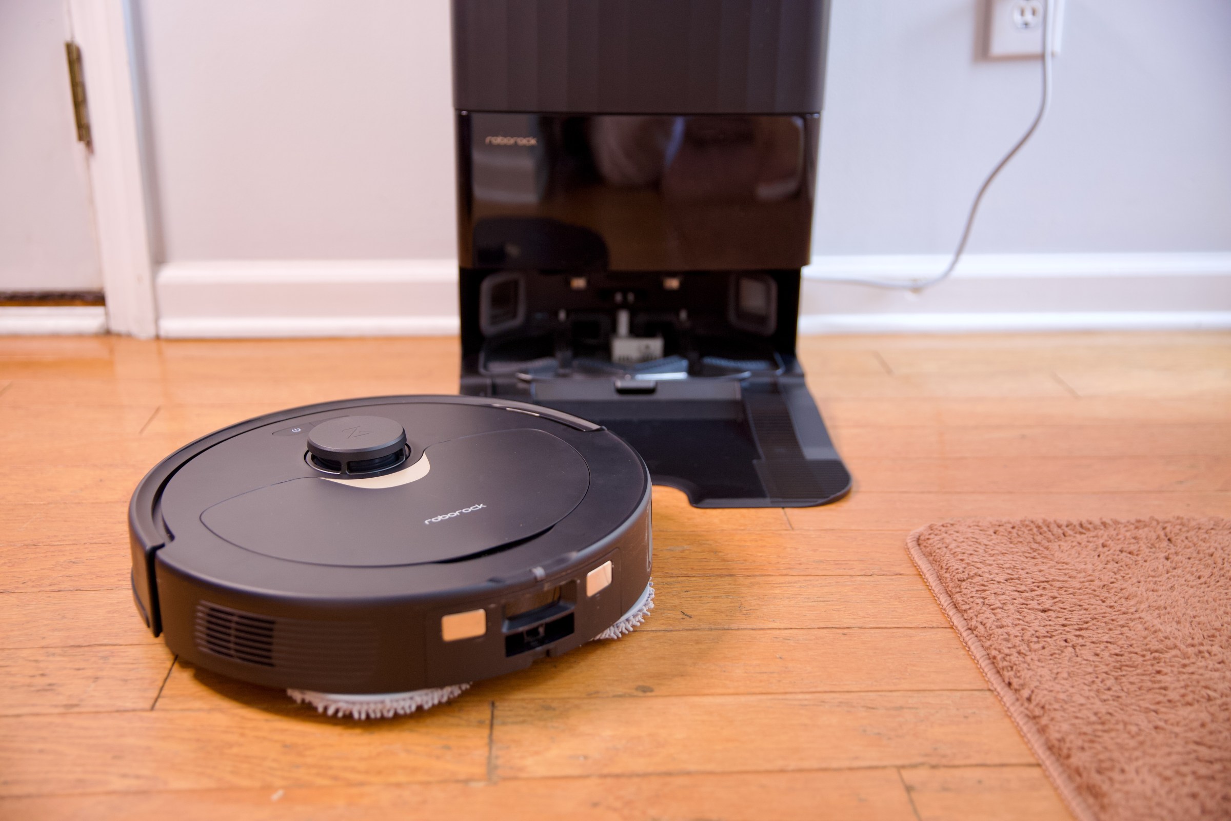 Roborock’s Q Revo robot vacuum sitting on a hardwood floor with its charging dock.