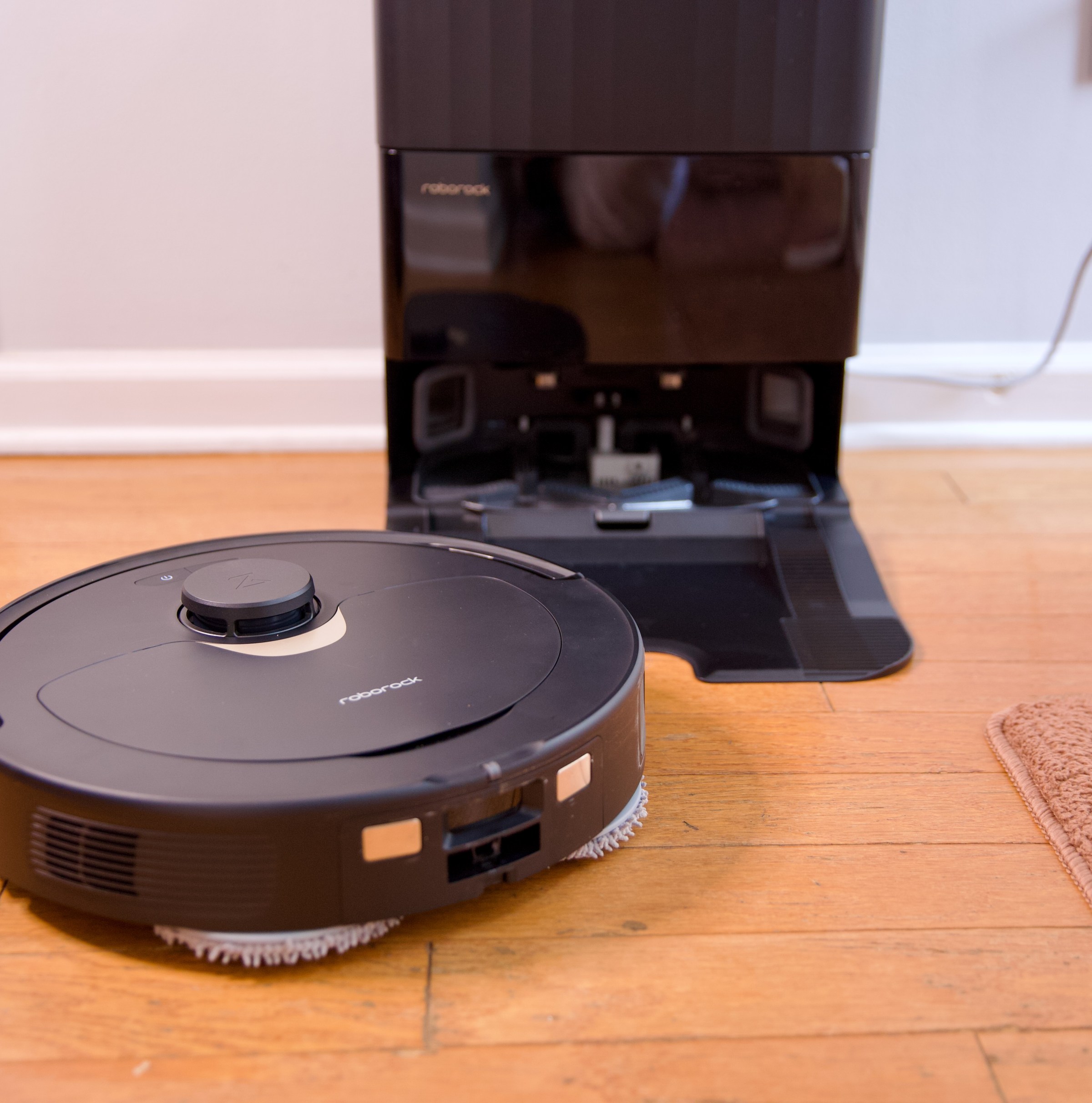 Roborock’s Q Revo robot vacuum sitting on a hardwood floor with its charging dock.