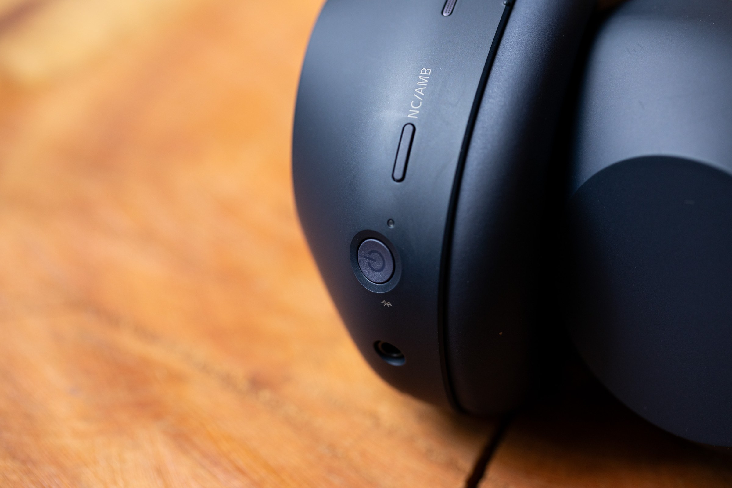 Close up of the underside of headphone earcup, with a round power button and an oblong noise-cancelling button.