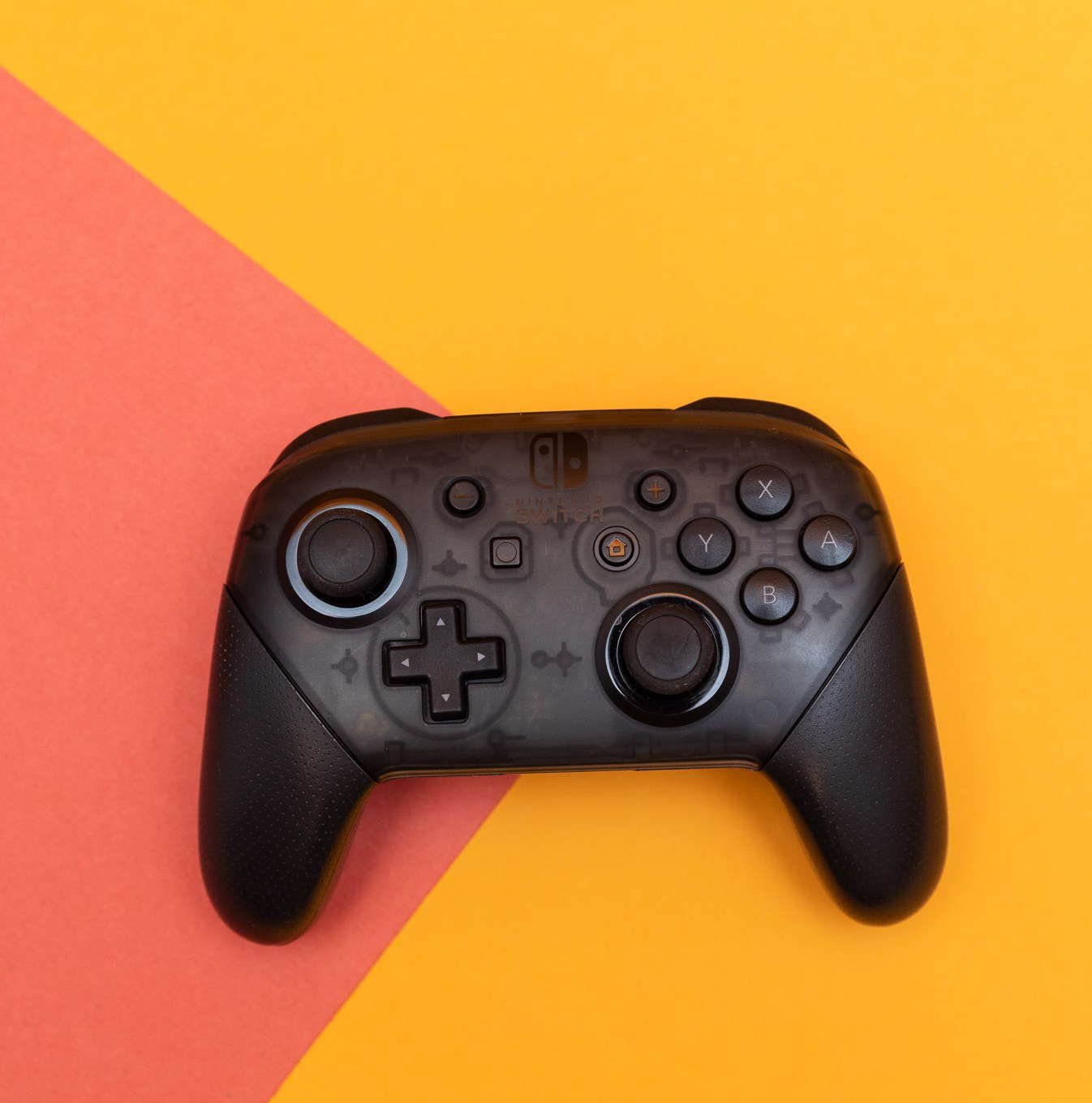 The Nintendo Switch Pro Controller sitting flat on a two-colored backdrop.