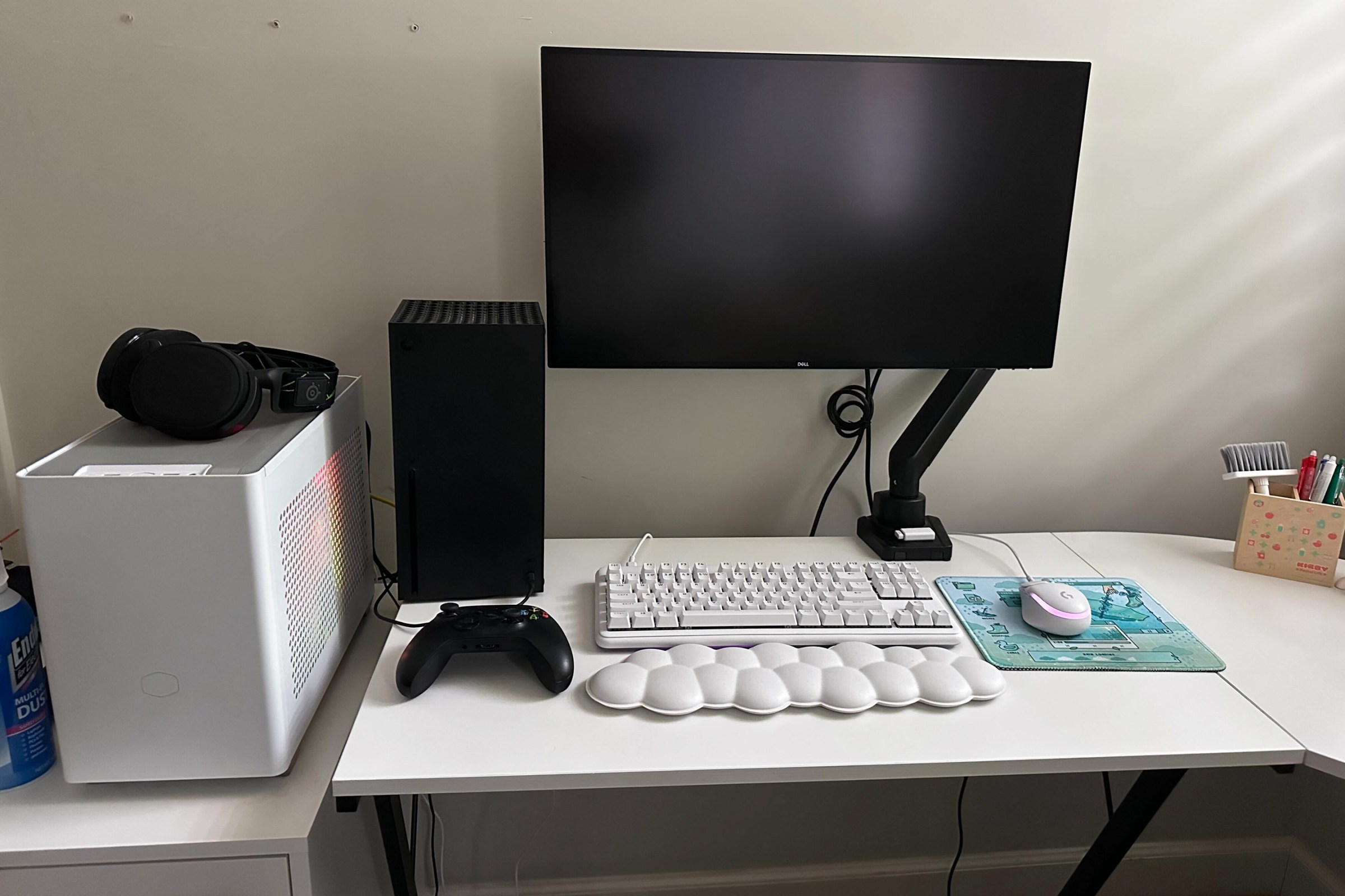 Desk with a large monitor, a console, a keyboard, and a wrist rest.