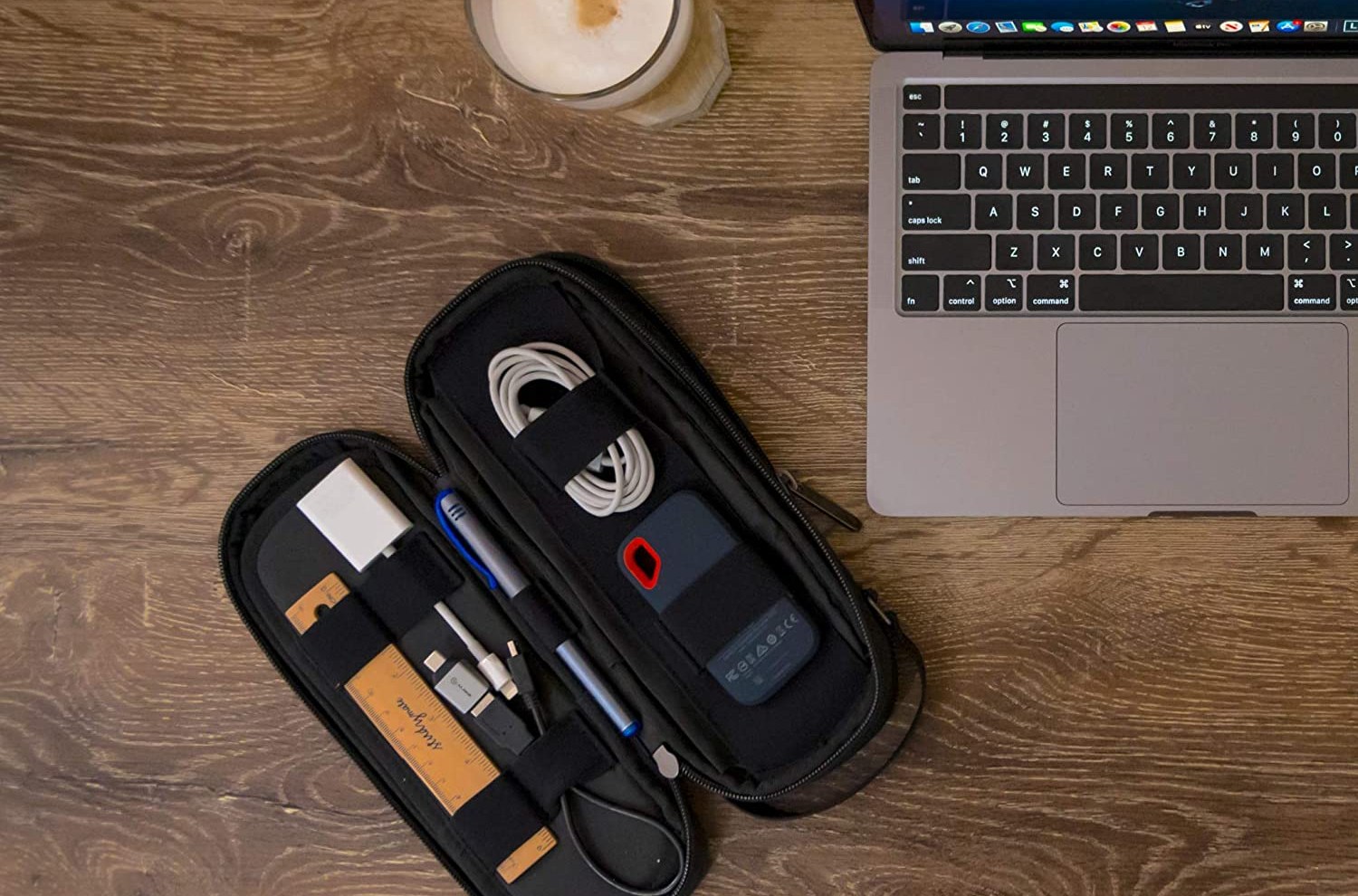 Open gadget bag filled with cords and other miscellany next to a candle and a laptop.