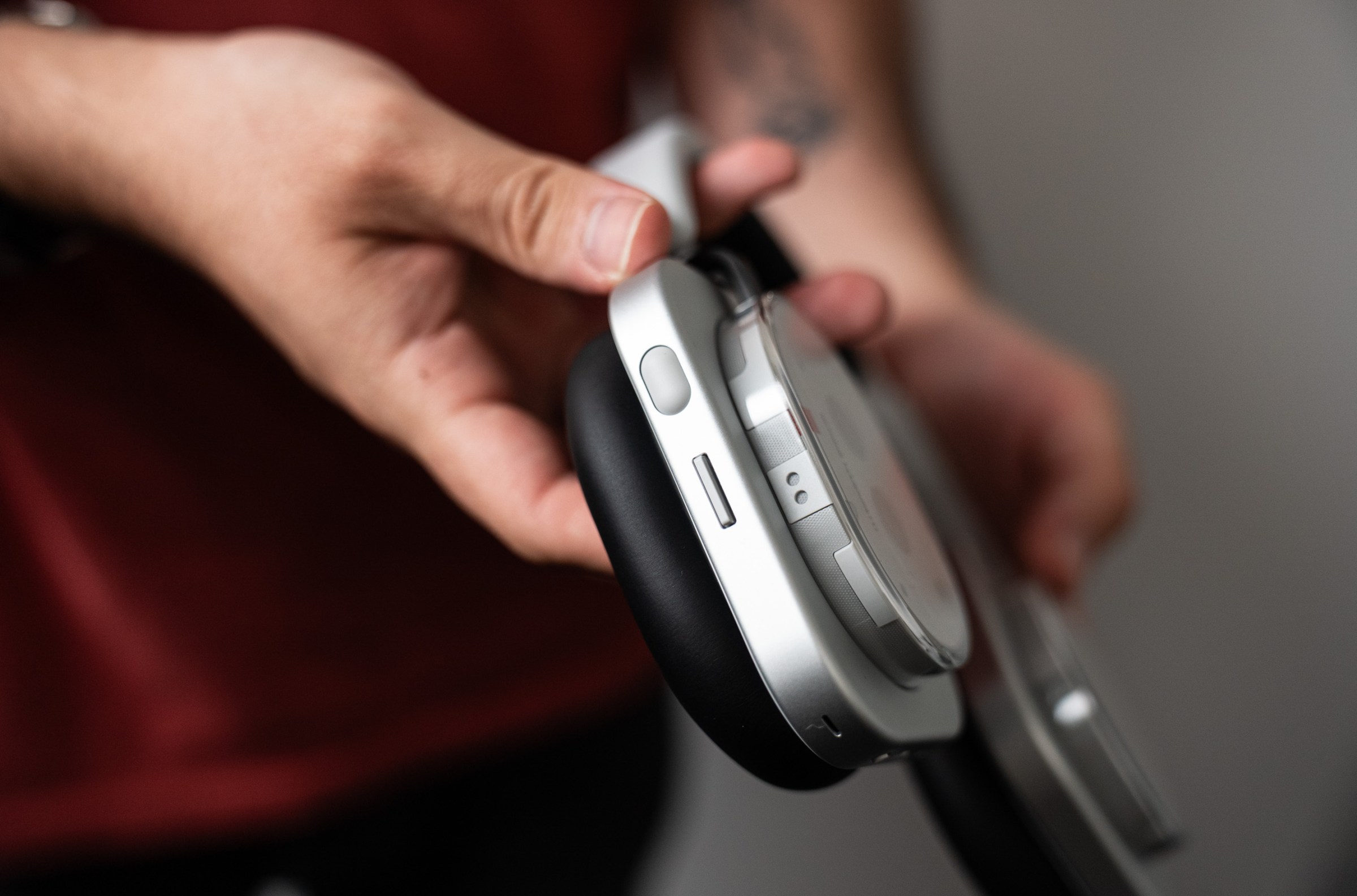 Side view of the right ear of the Nothing headphones, displaying two buttons; one tictac sized rubber piece, and another switch below it.