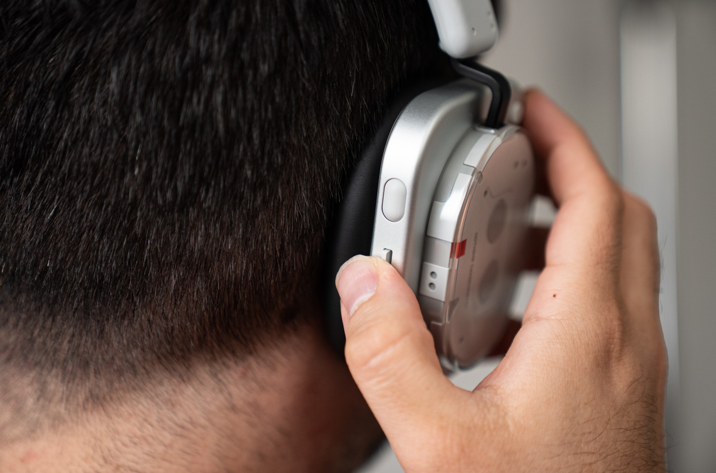 A view of the back of the headphones while wearing them. A thumb against the paddle switch.