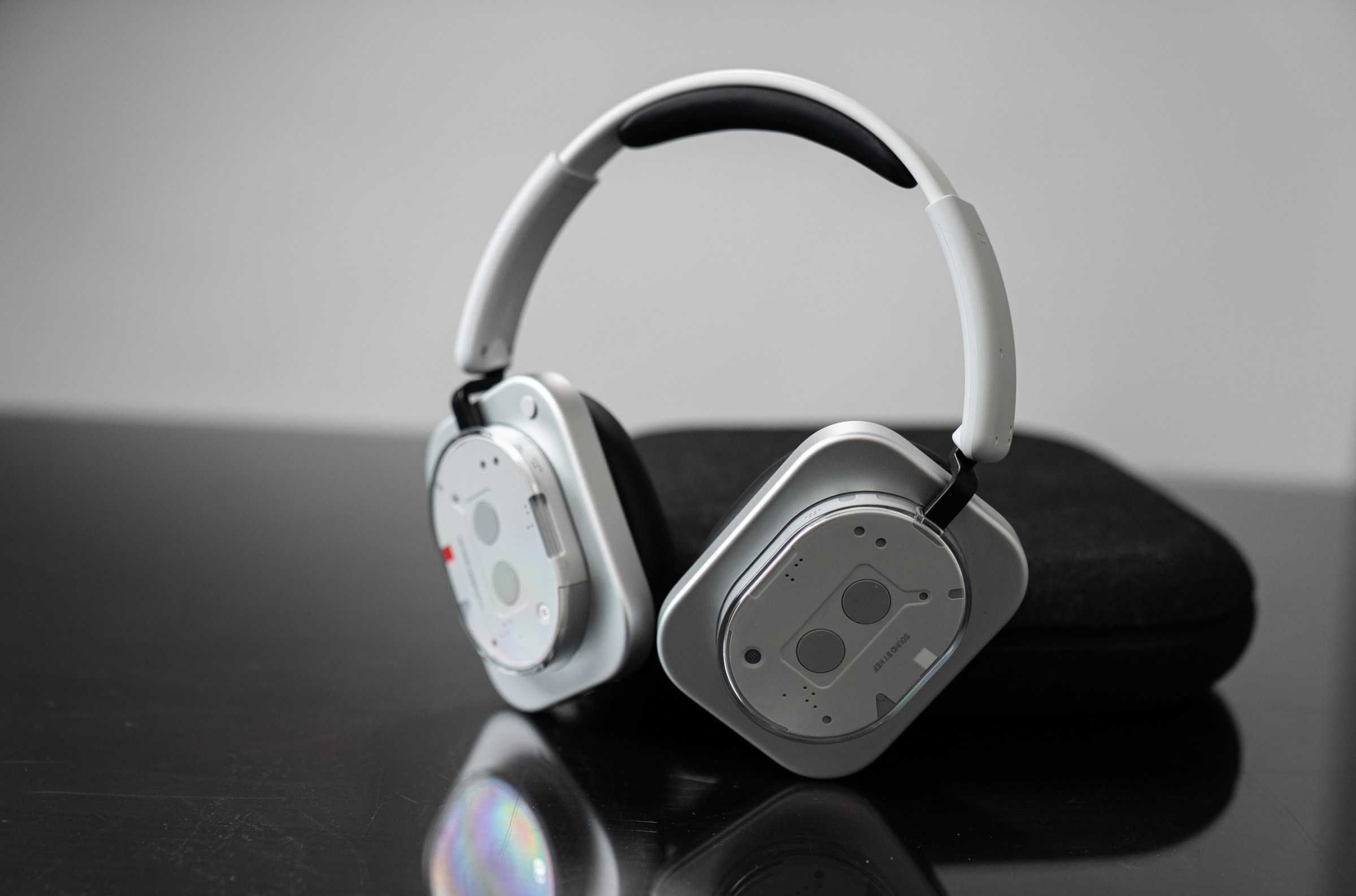 Nothing headphones standing upright on a black table.