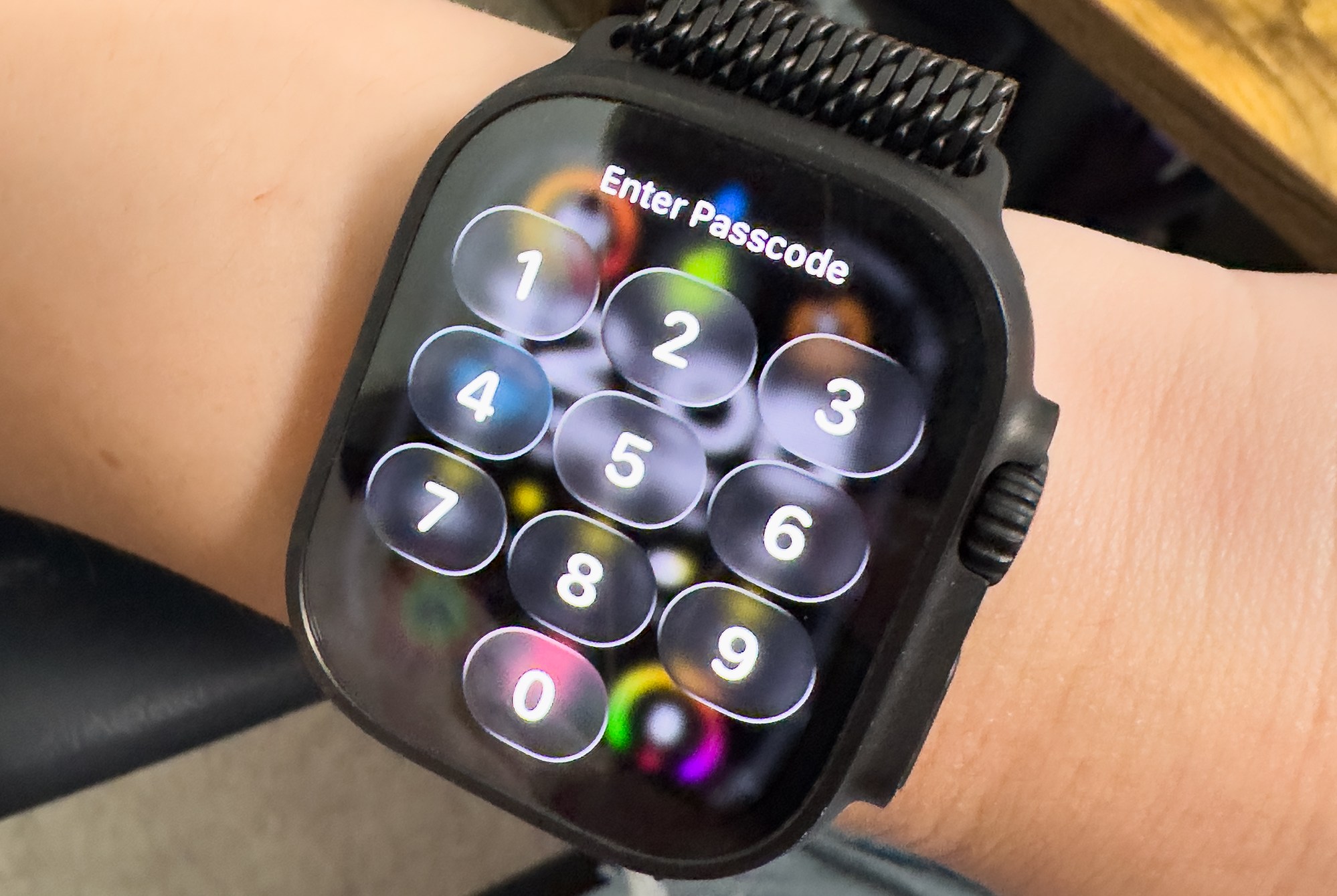 CLose up of the ENter passcode screen on watchOS 26 which prominently shows the Liquid Glass effect