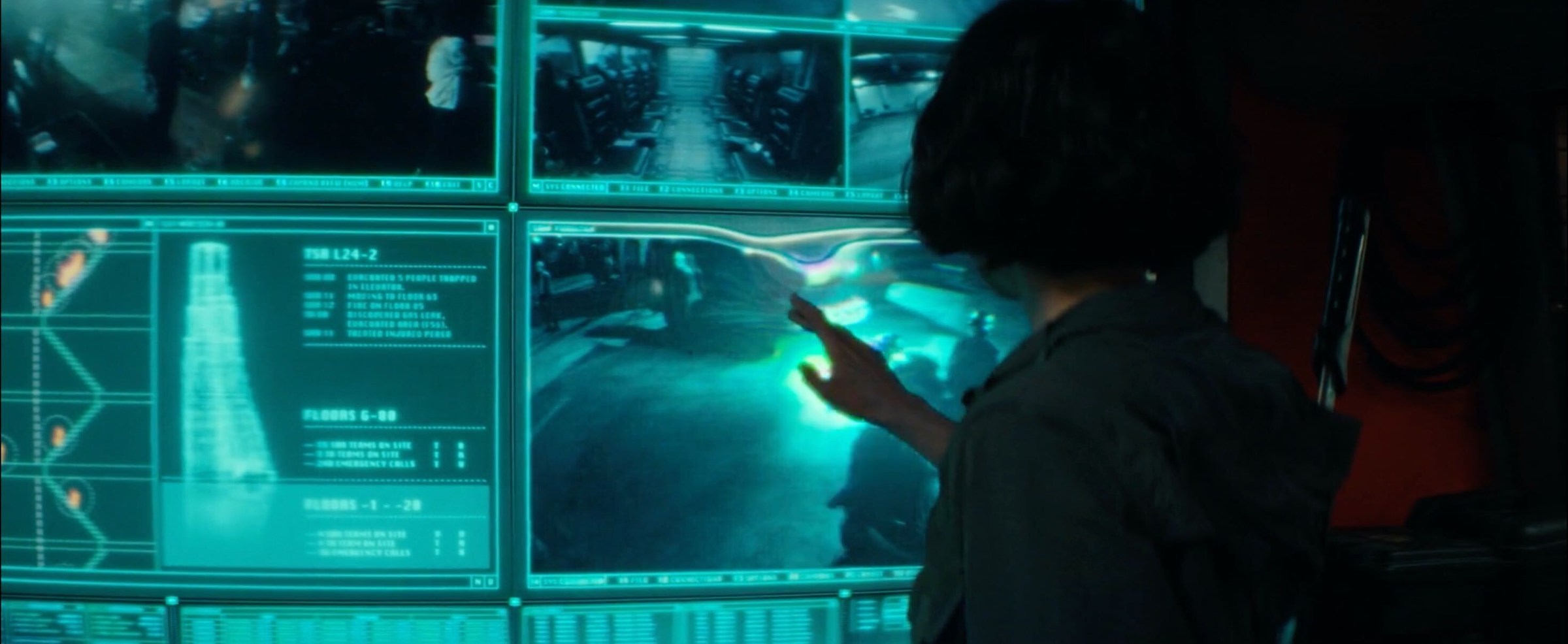 A woman interacting with an array of touchscreens in a control room.