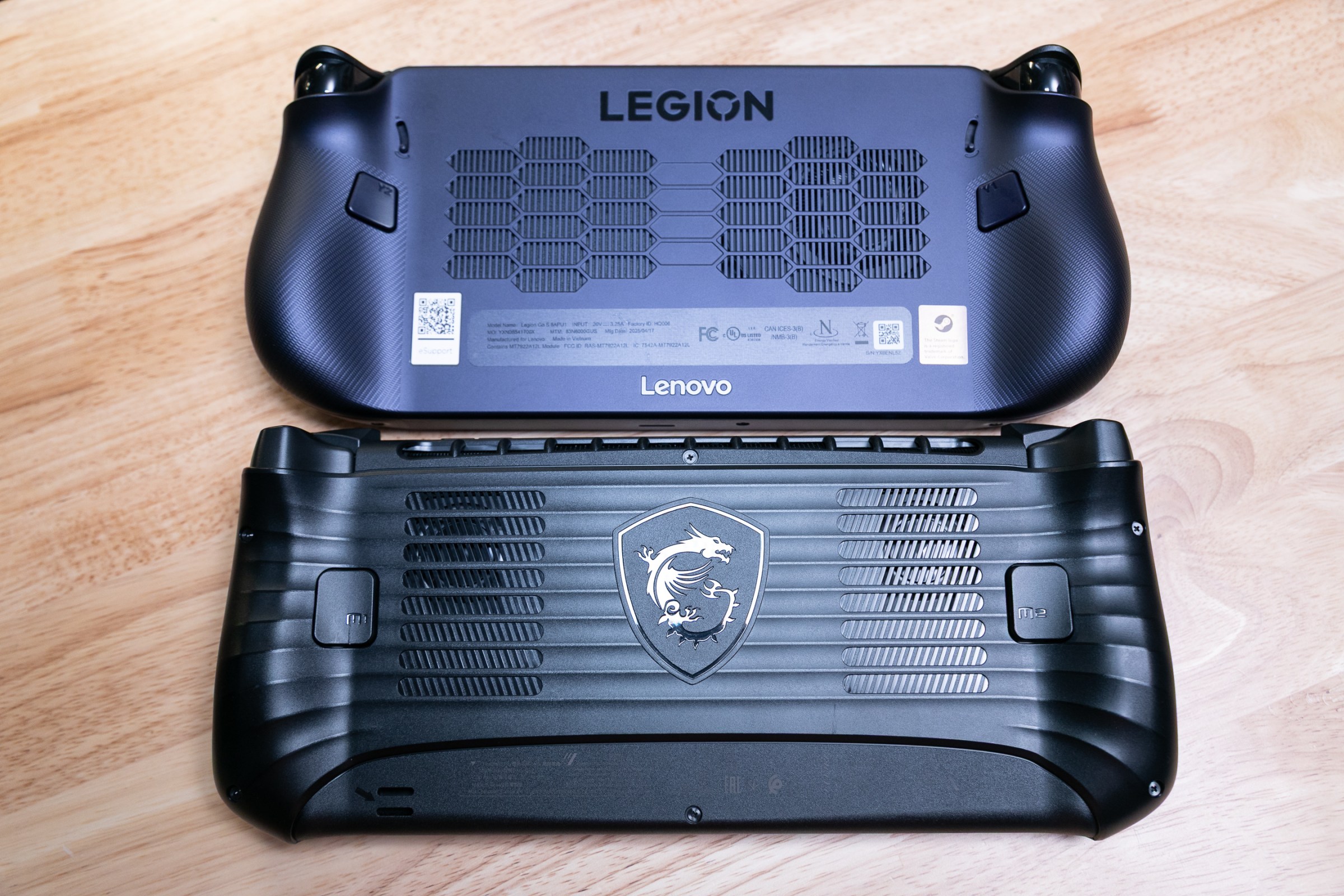 The backs of the MSI Claw 8 AI Plus and Lenovo Legion Go S, two black handhelds, to show size and grip comparison