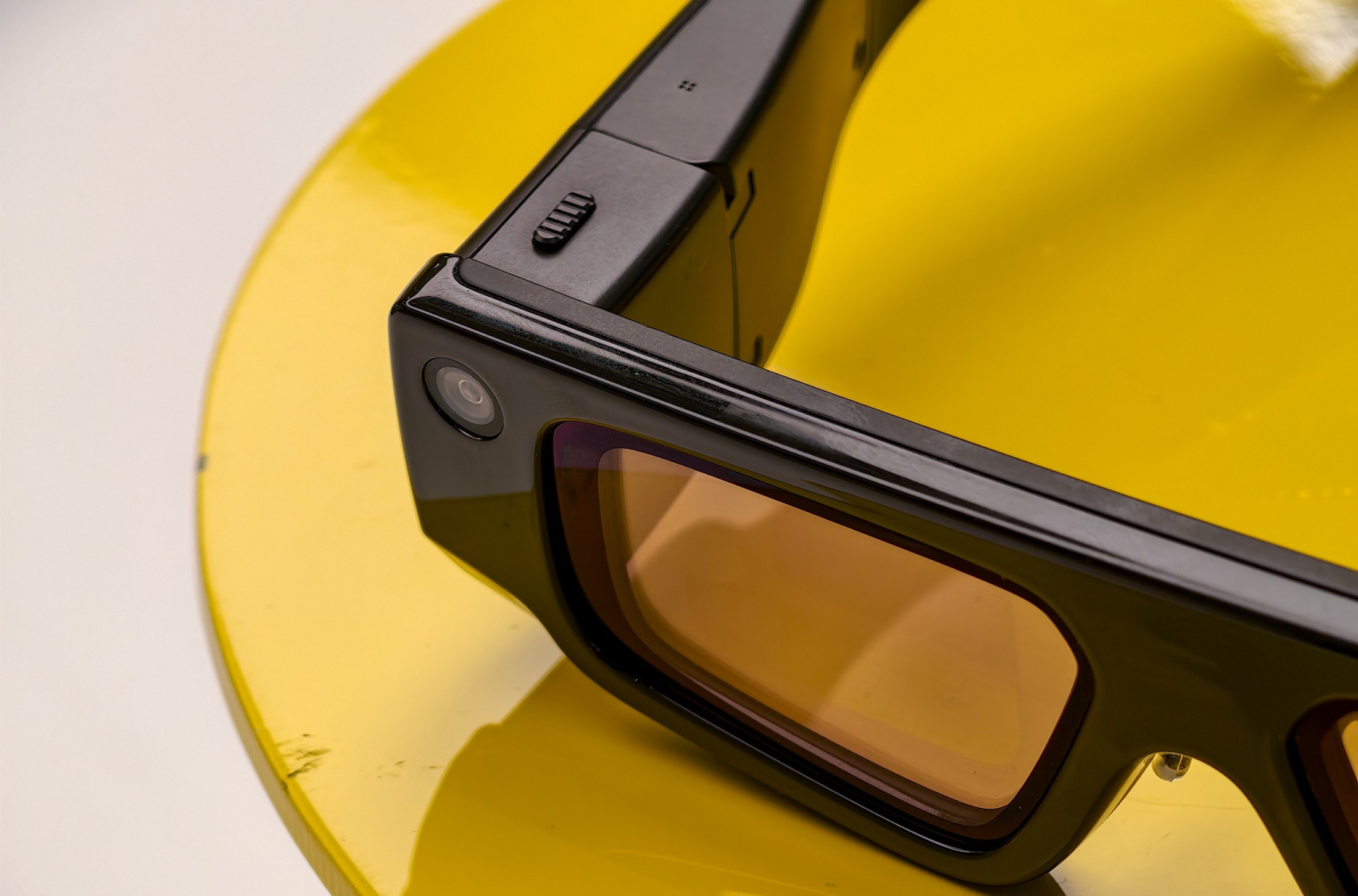 Snap Spectacles on a yellow table, showing the camera and button
