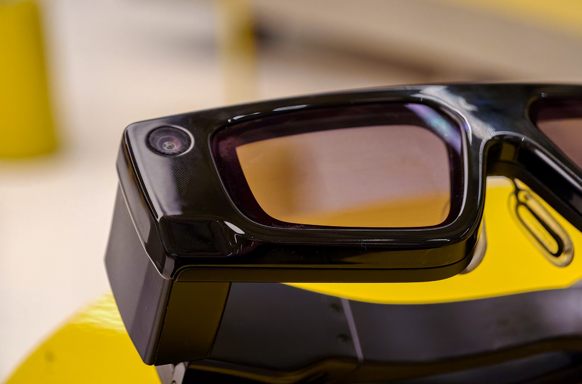 Snap Spectacles on a yellow table, showing the camera next to a lens