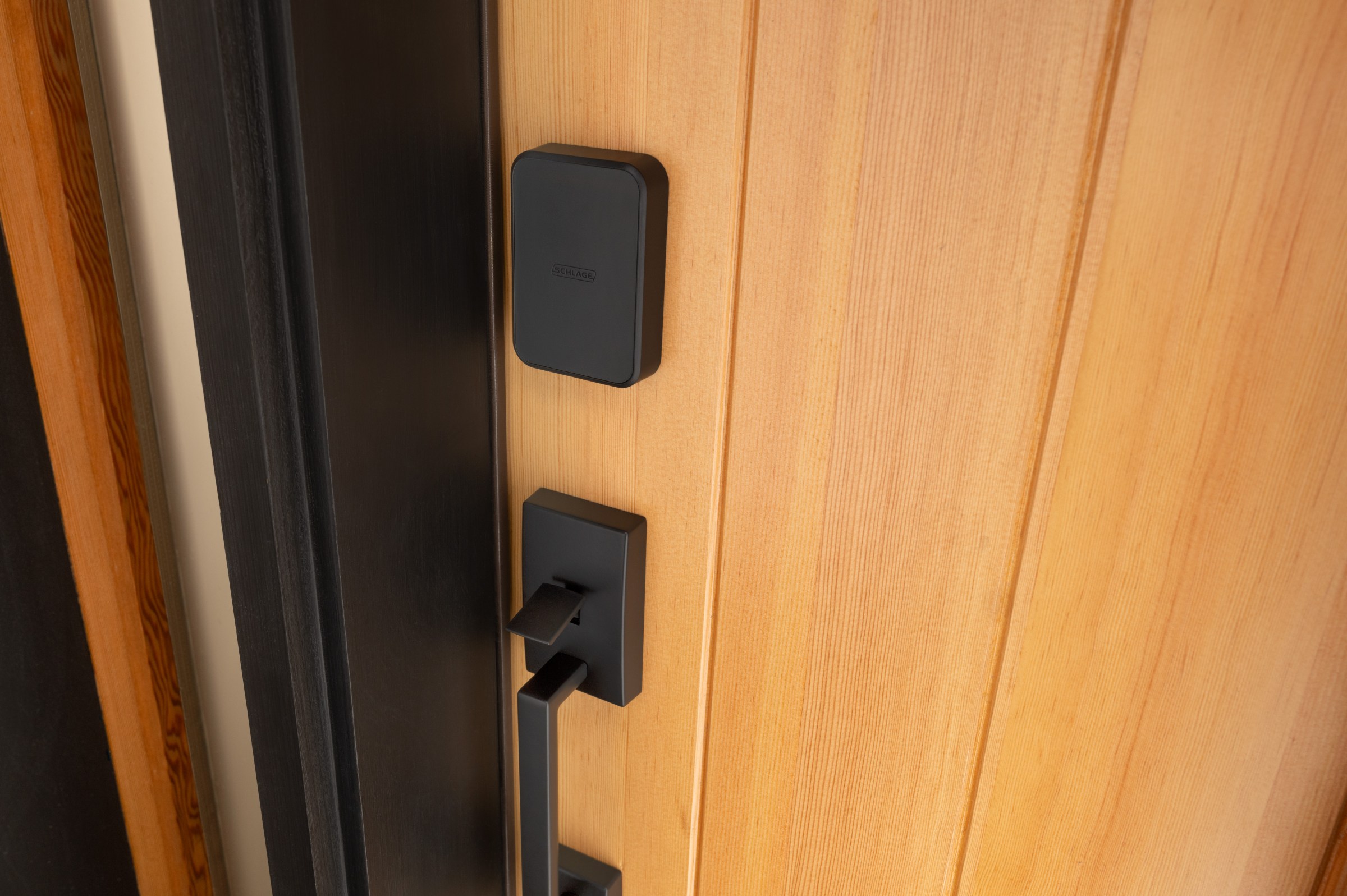 A black door lock on a light brown door.