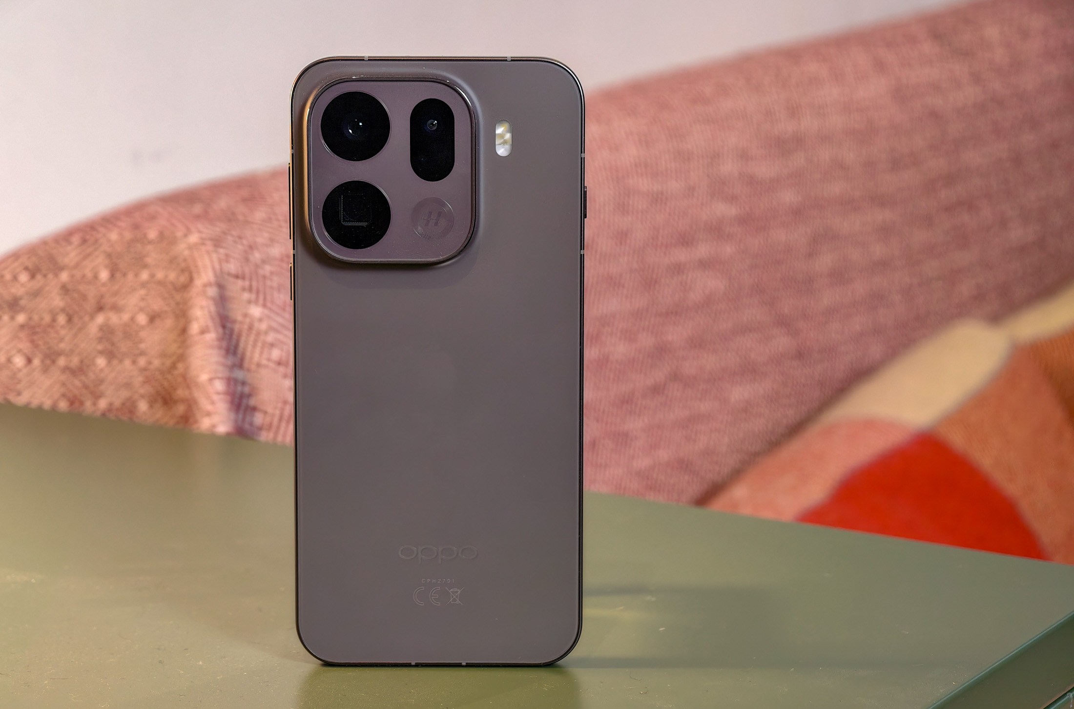 Oppo Find X9 Pro resting on a green table in front of a sofa