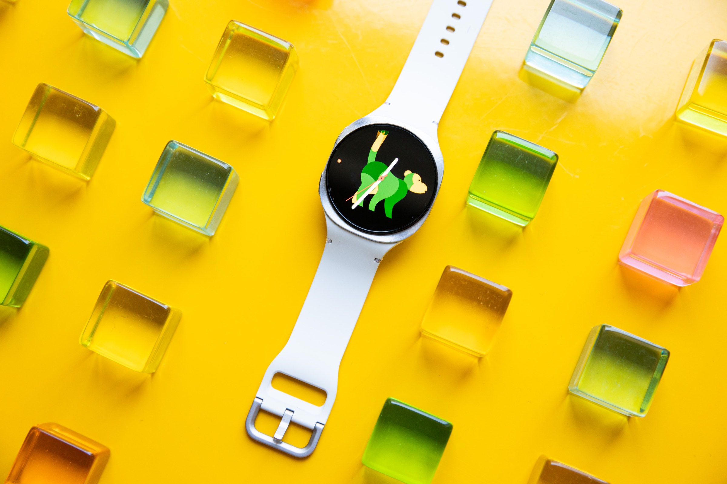 Wide view of the Samsung Galaxy Watch 8 on a yellow table with colorful green, yellow, orange, and pink acrylic blocks around it.