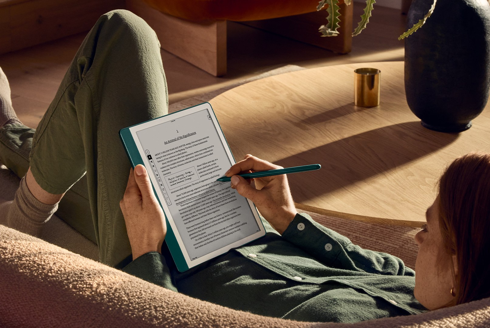 A person on a couch reading on a Kindle Scribe.
