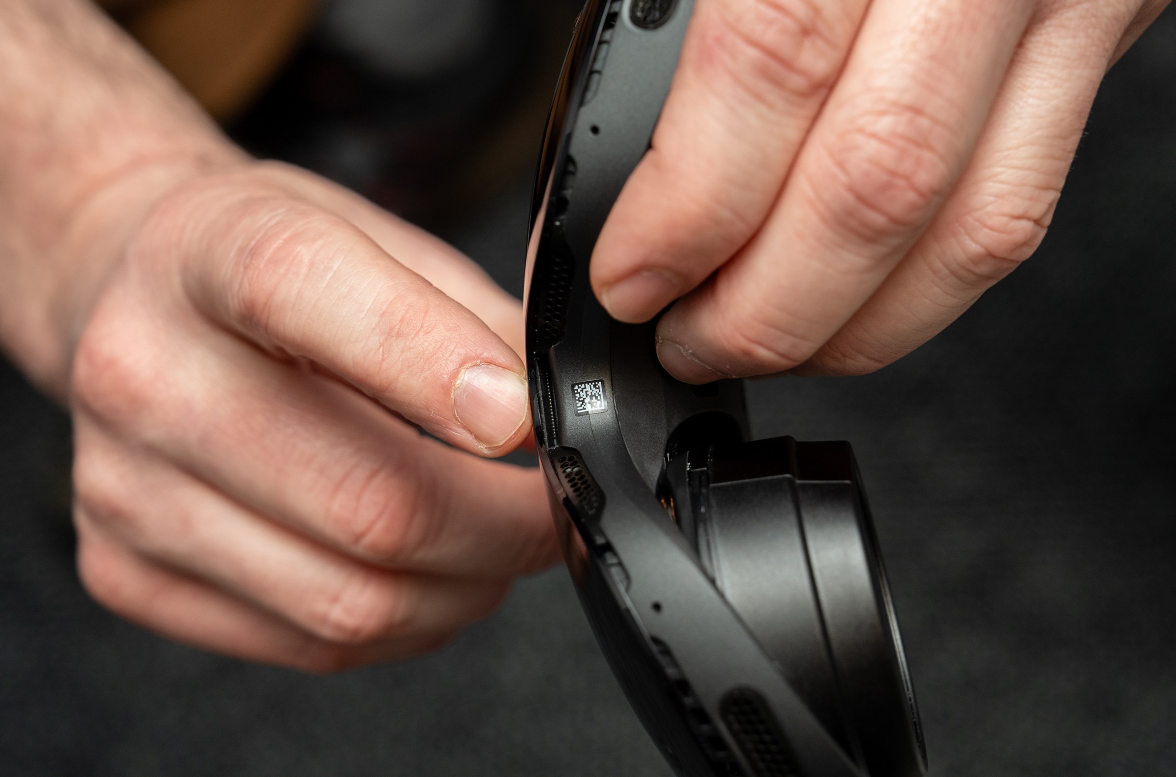 A person holding a Steam Frame and pointing at an expansion port on the nose of the headset.
