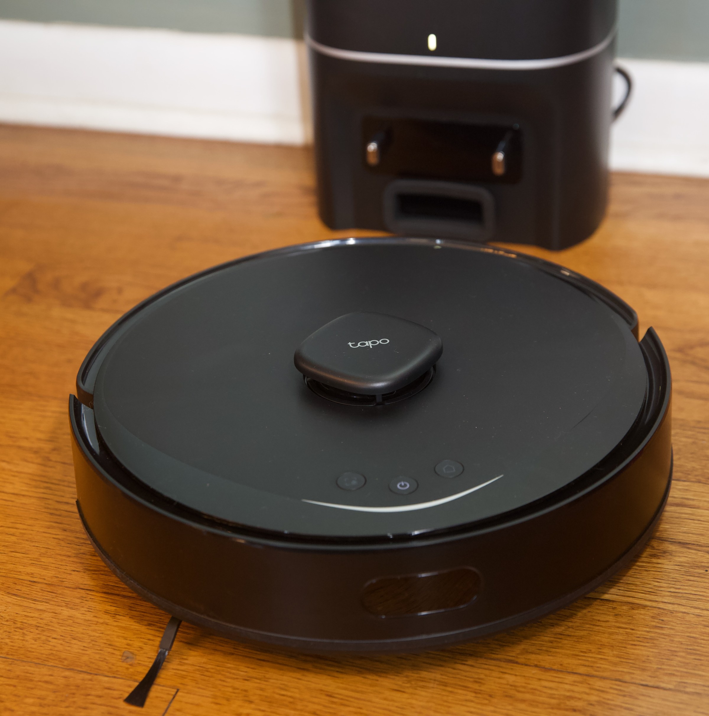 A black robot vacuum on a hardwood floor