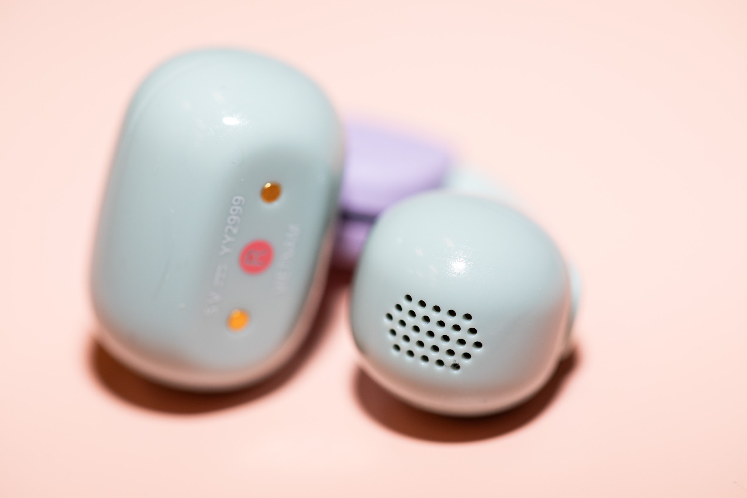 A closeup of the Sony LinkBuds Clip earbuds on a peach colored surface.