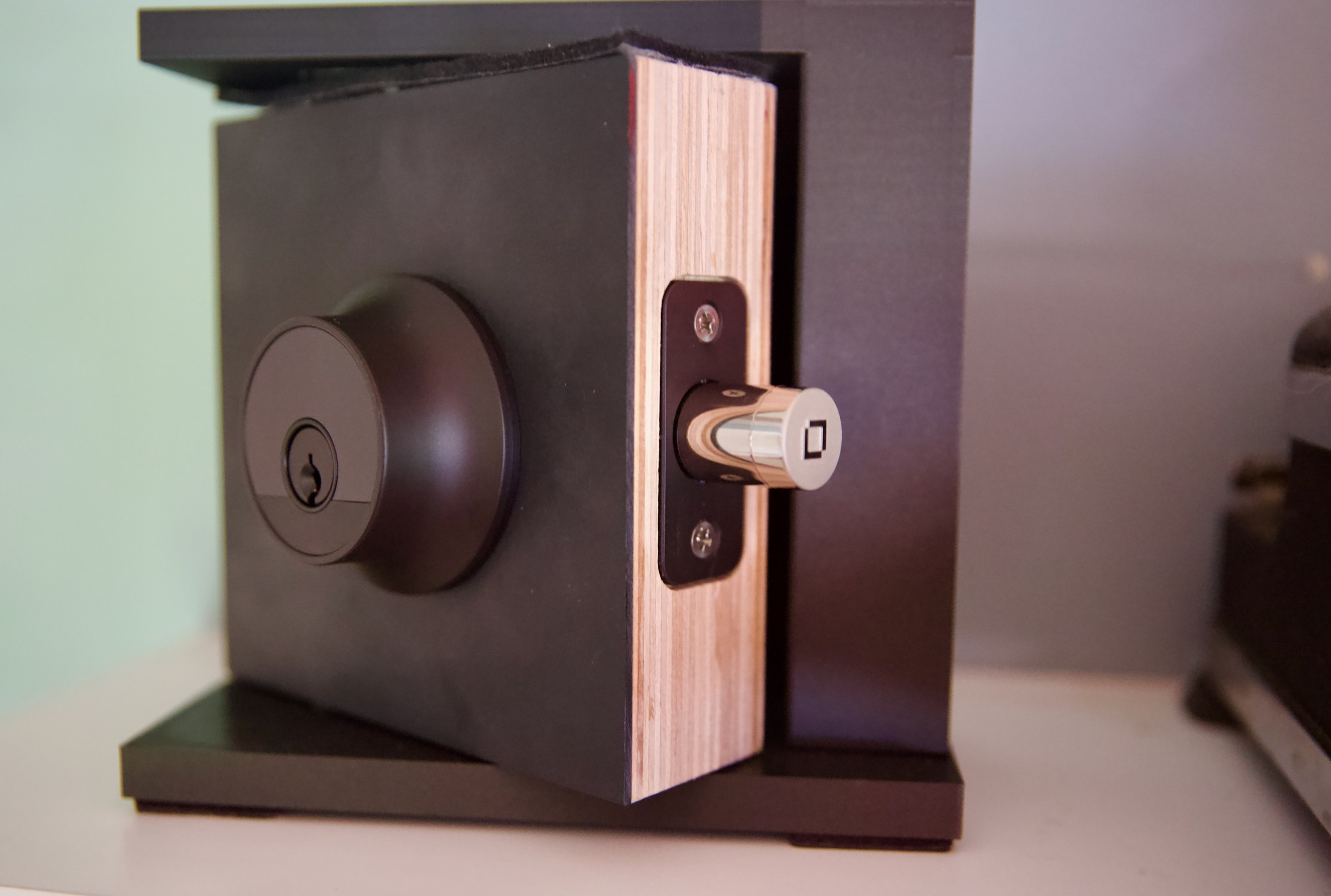 A black smart lock in a small black door on a shelf.