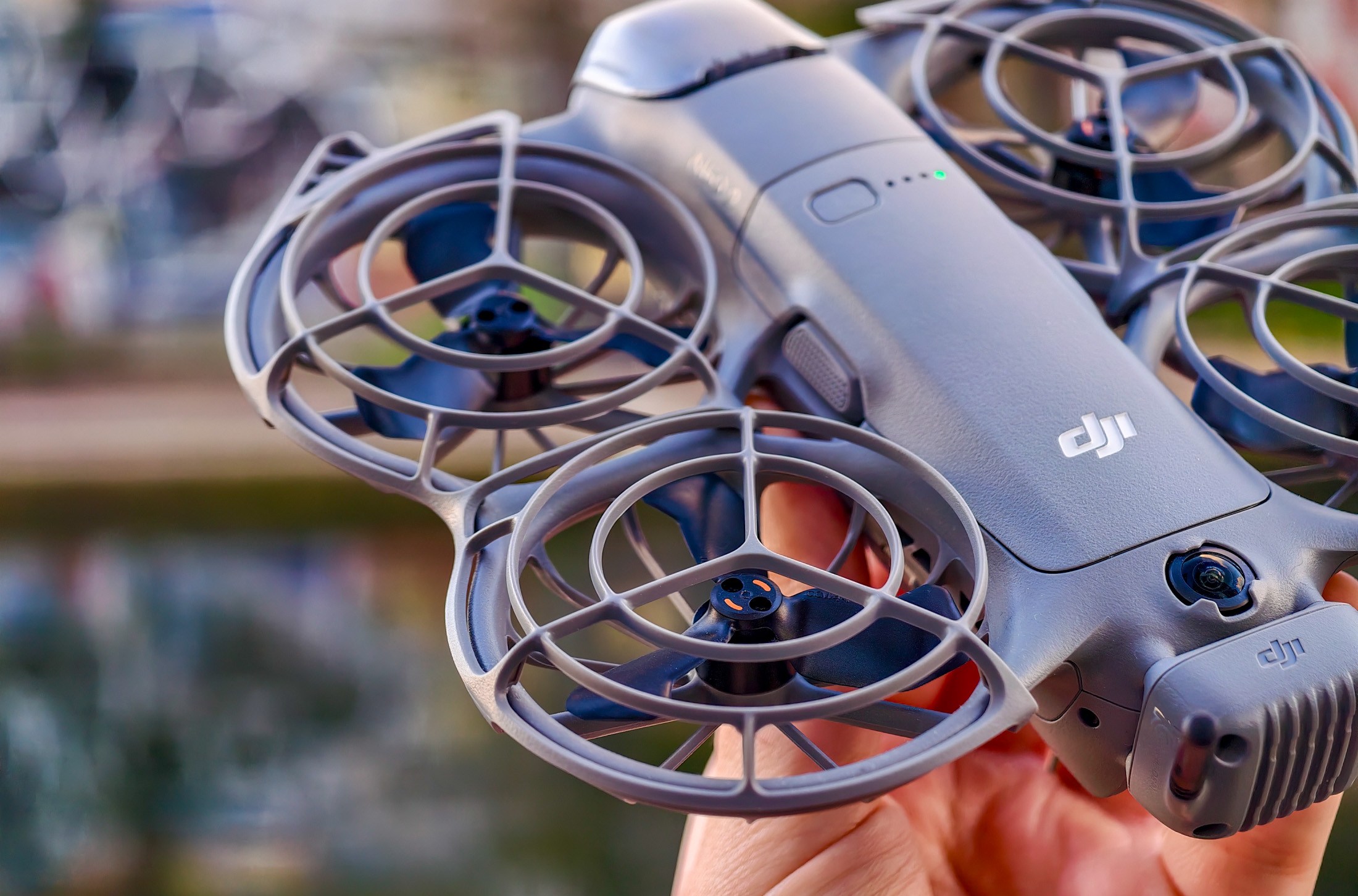 Photo of DJI Neo 2 held in a hand in front of a canal, showing the propellers