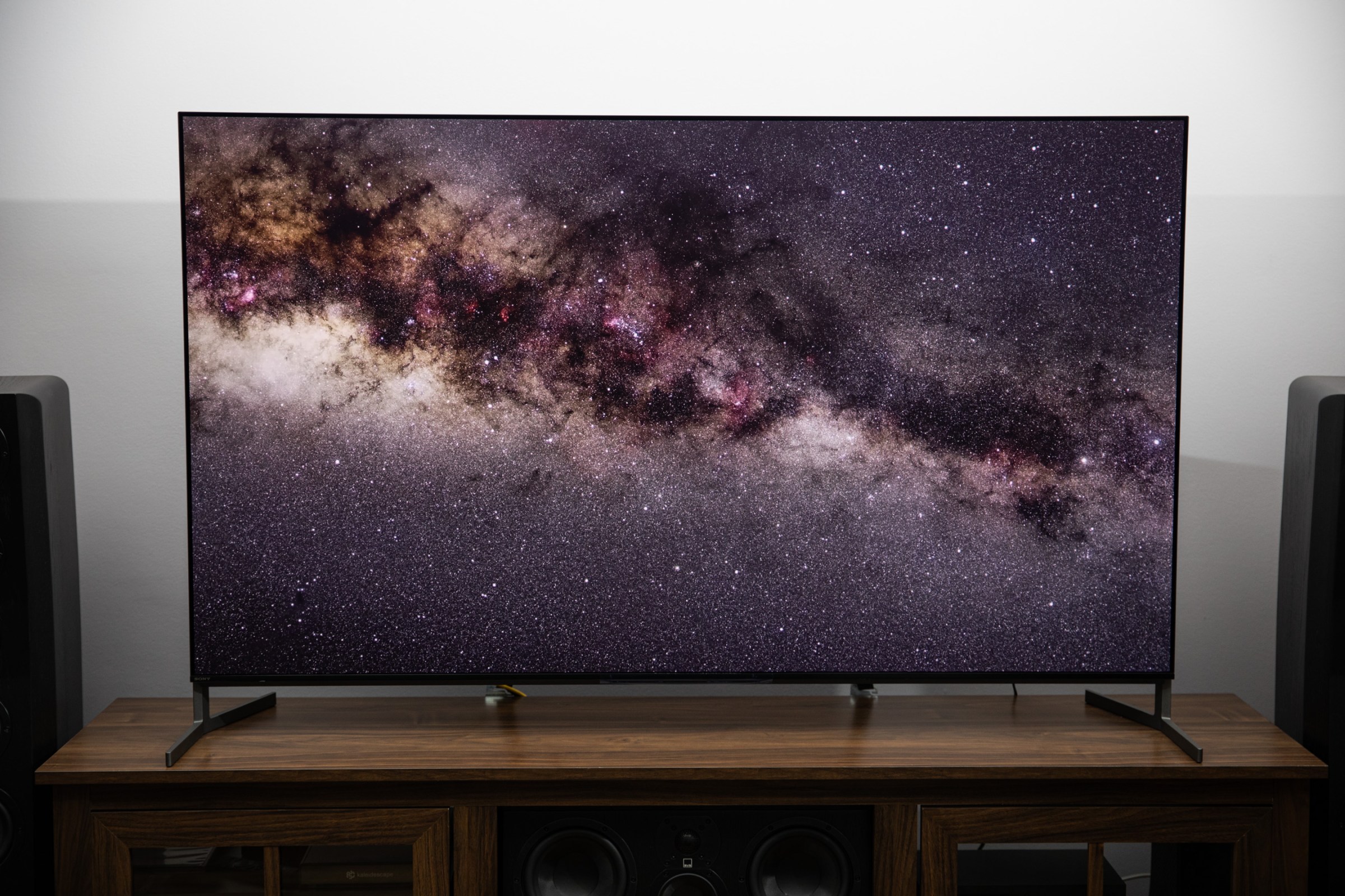 The Sony Bravia 8 II on a wooden TV stand displaying a starfield.