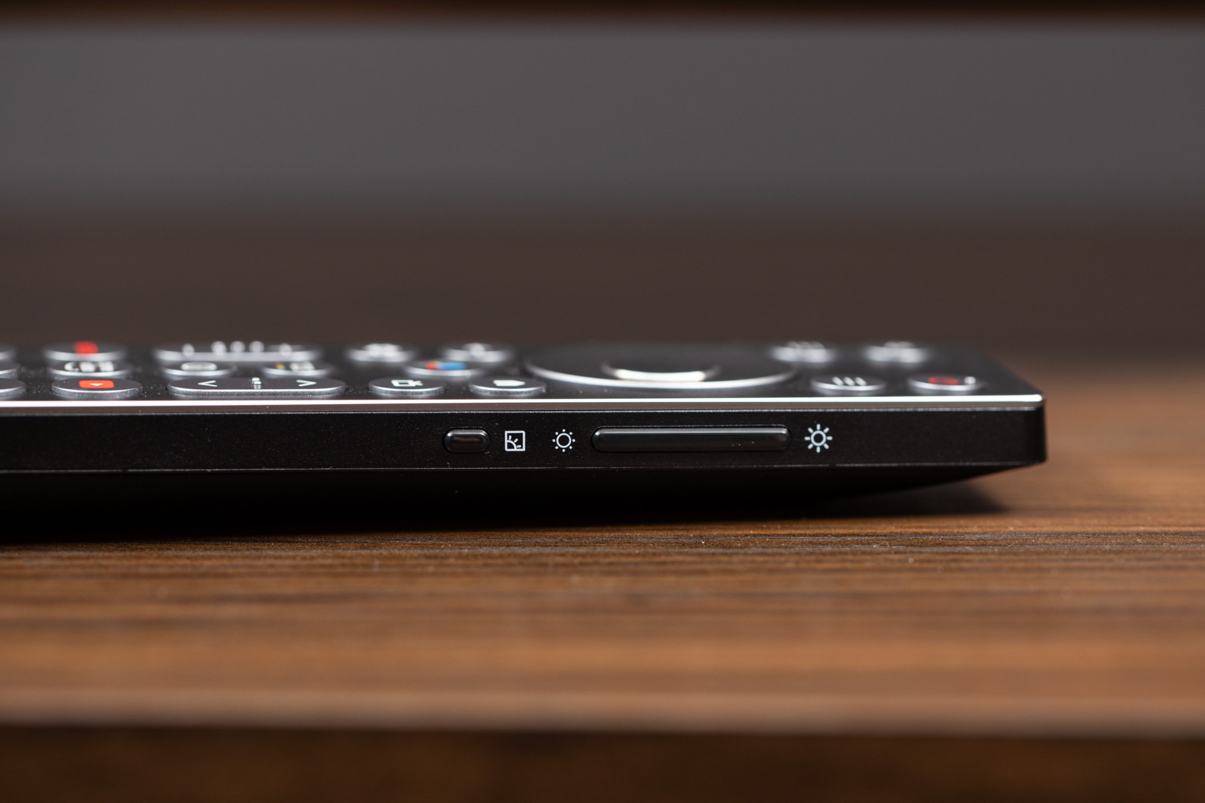A closeup of the brightness and picture mode buttons on the side of the TCL X11L remote.