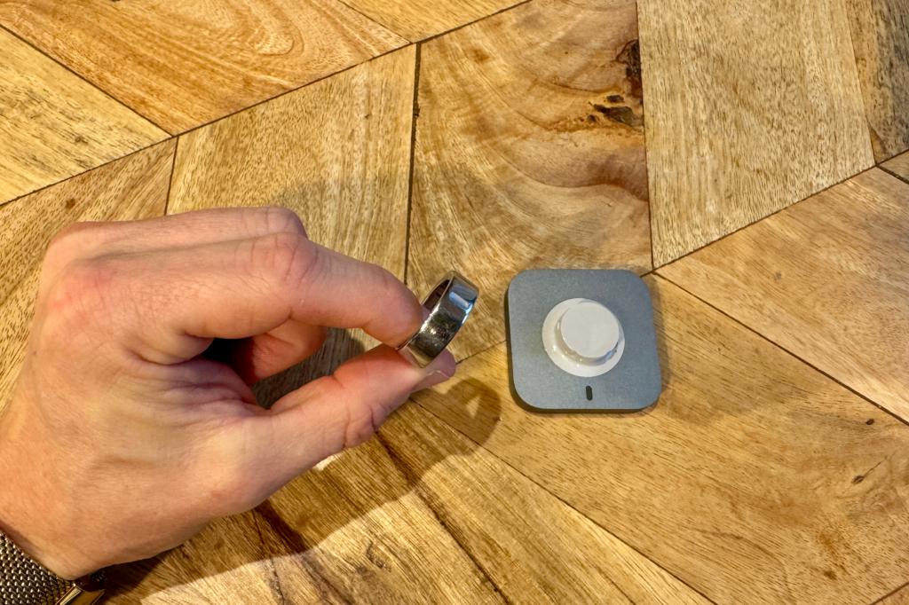 Oura Ring 4 in hand next to charger