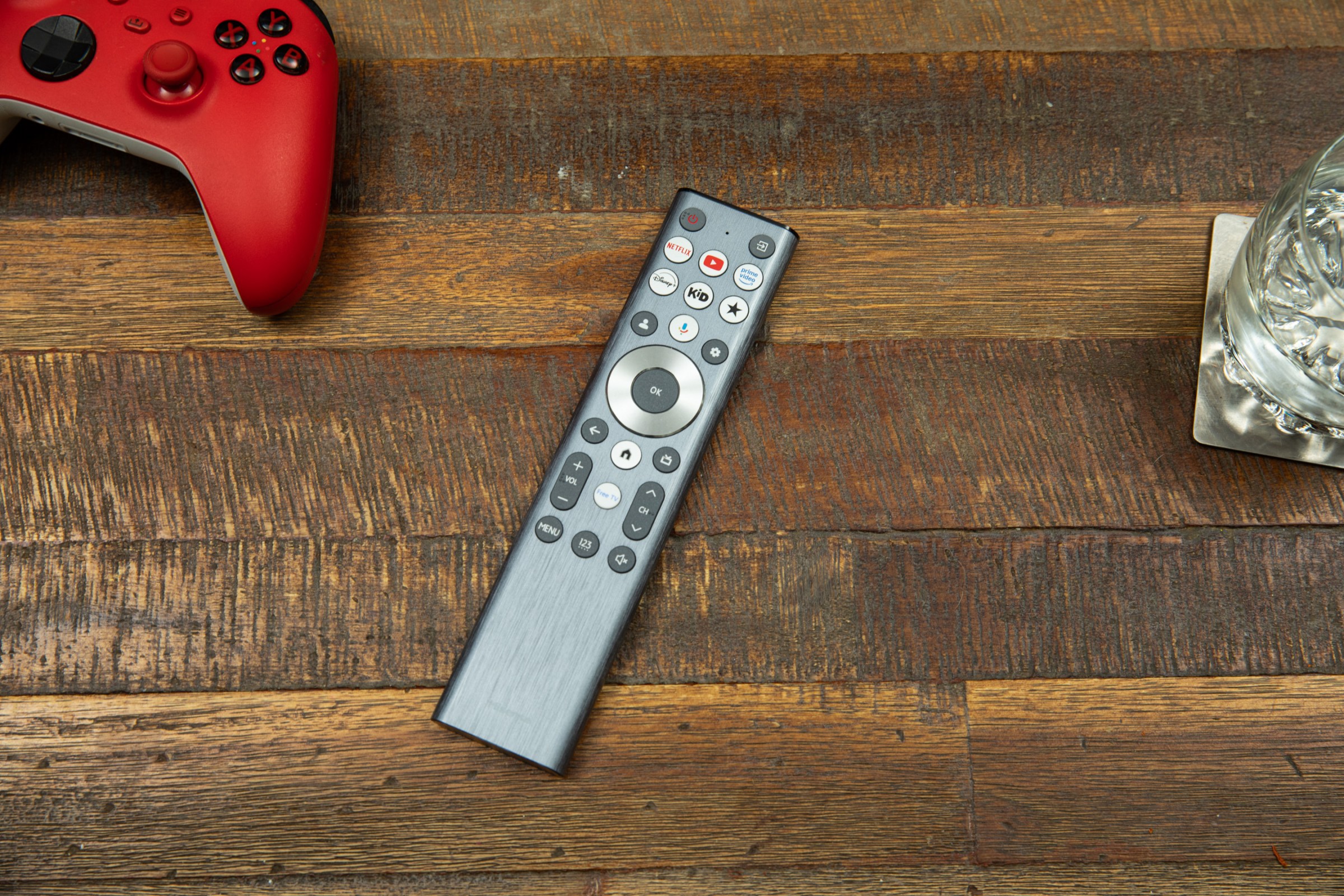 The Hisense U7SG remote on a wooden coffee table next to a water glass and a red Xbox controller.