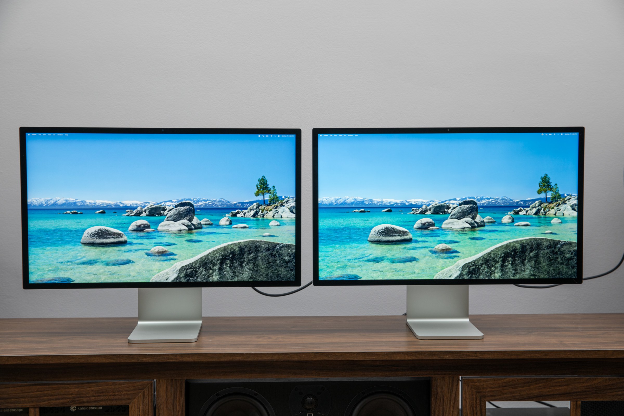 The Apple Studio Display XDR and Studio Display side by side on a wooden table.