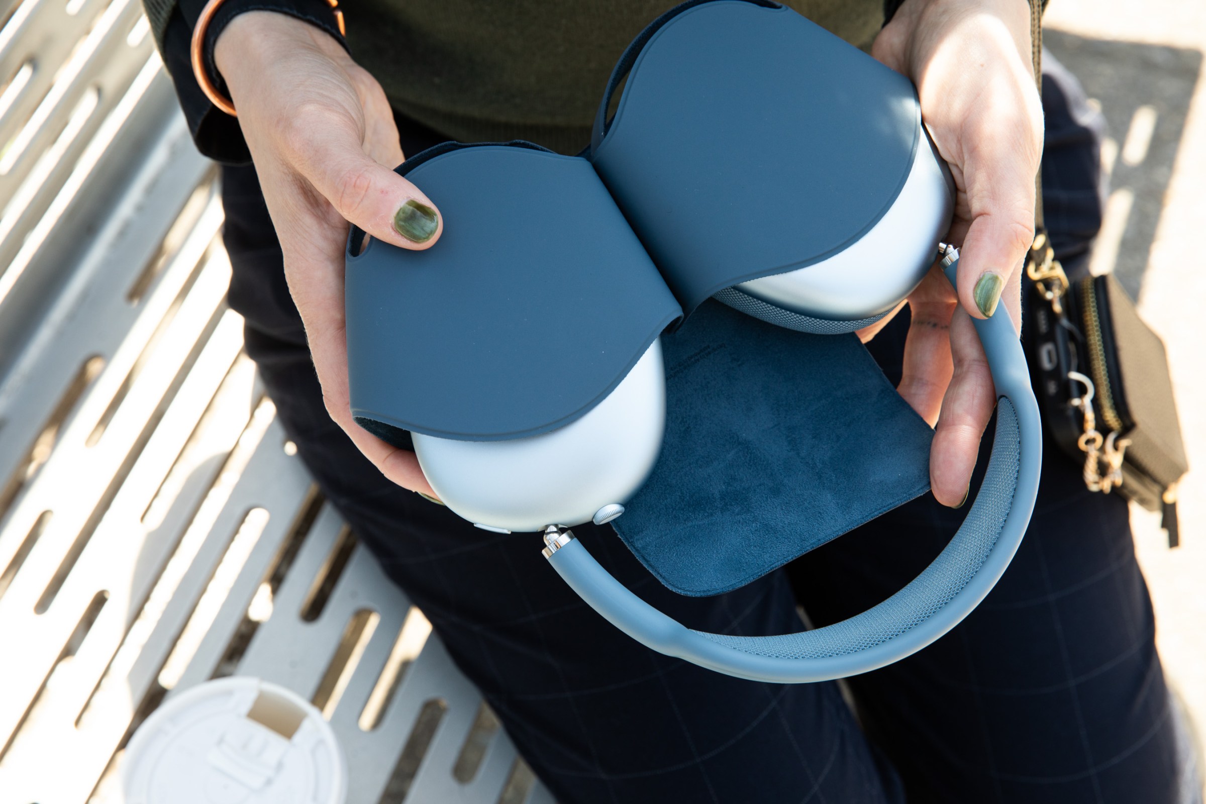 Hands holding the blue Apple AirPods Max 2 in their case.