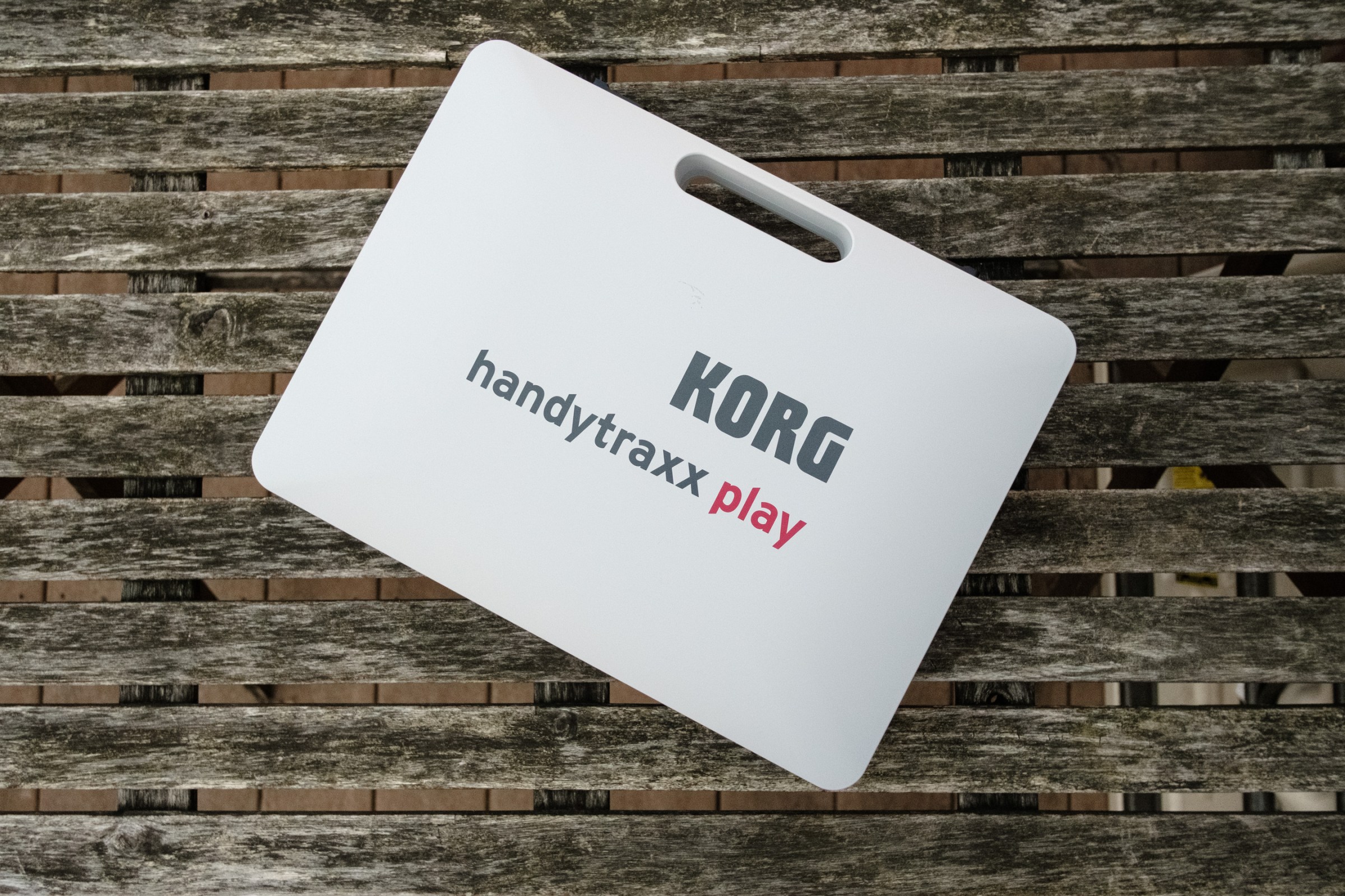 The Korg Handytraxx Play closed and on a word deck table.