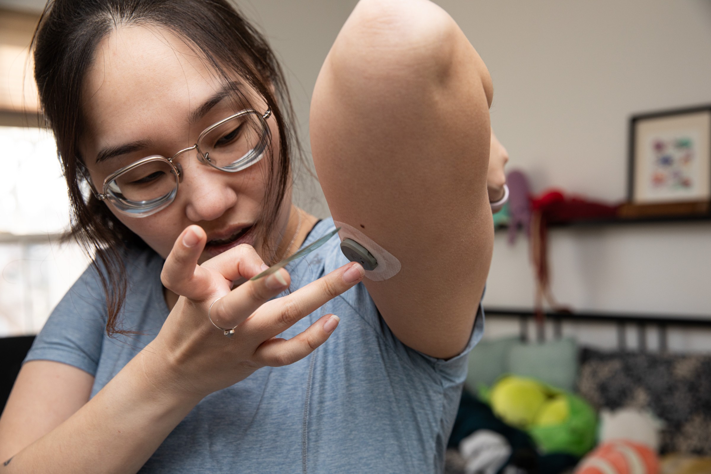 Senior reviewer Victoria Song applying a Dexcom Stelo CGM to the bottom of her arm.