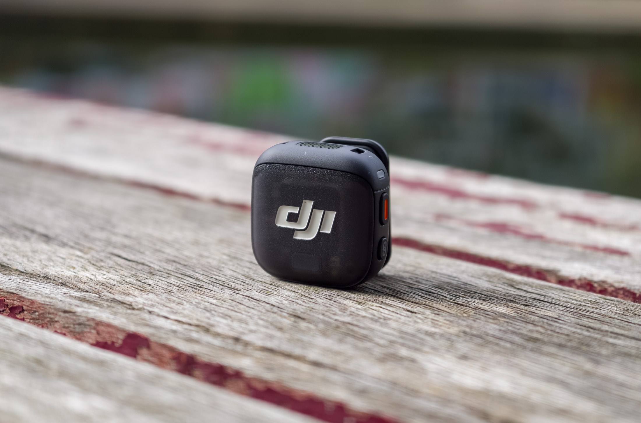 Photo of the DJI Mic 3 on a wooden table in front of a canal