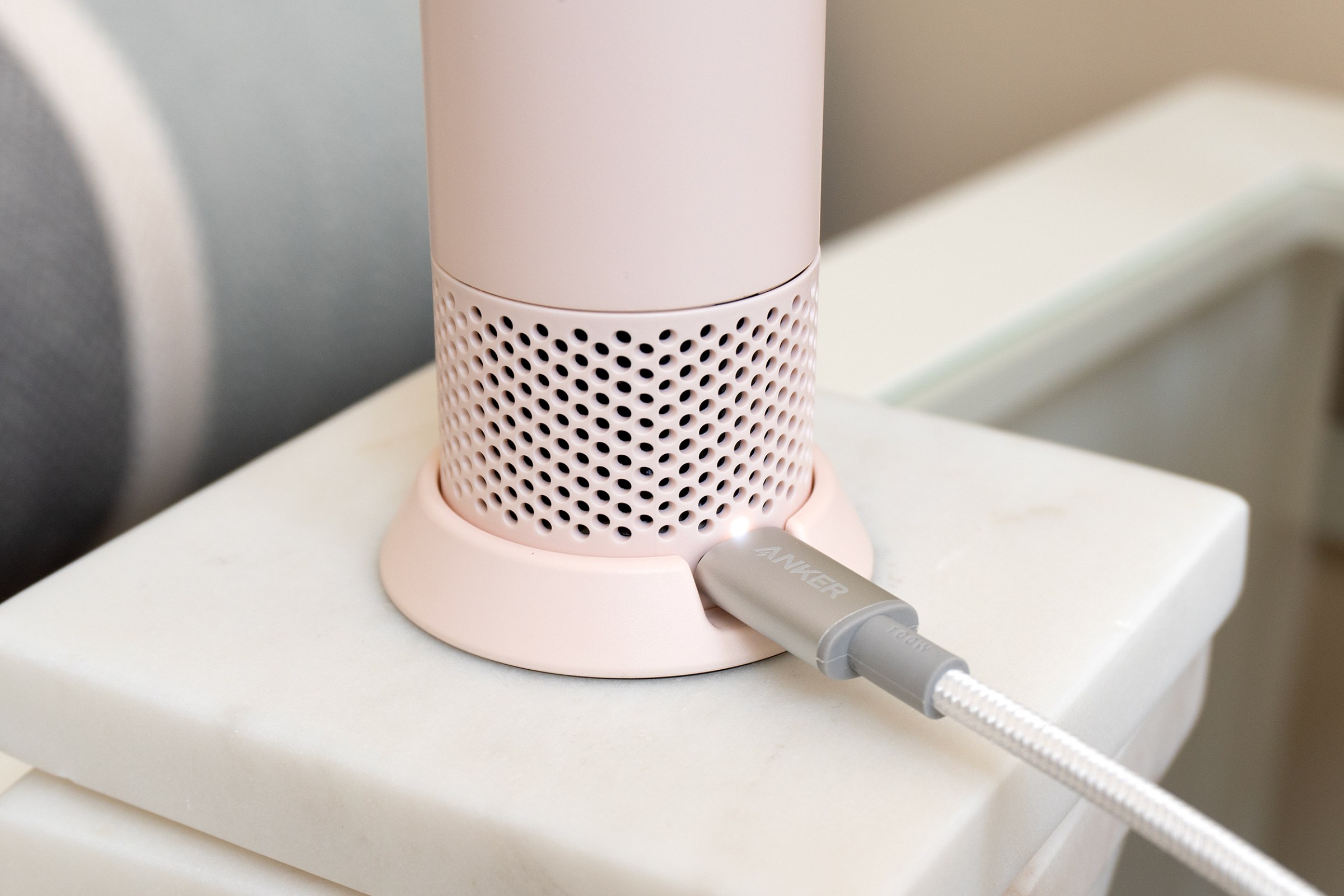 A USB-C cord plugged into the back of the Dyson HushJet Mini Cool attached to a stand accessory.