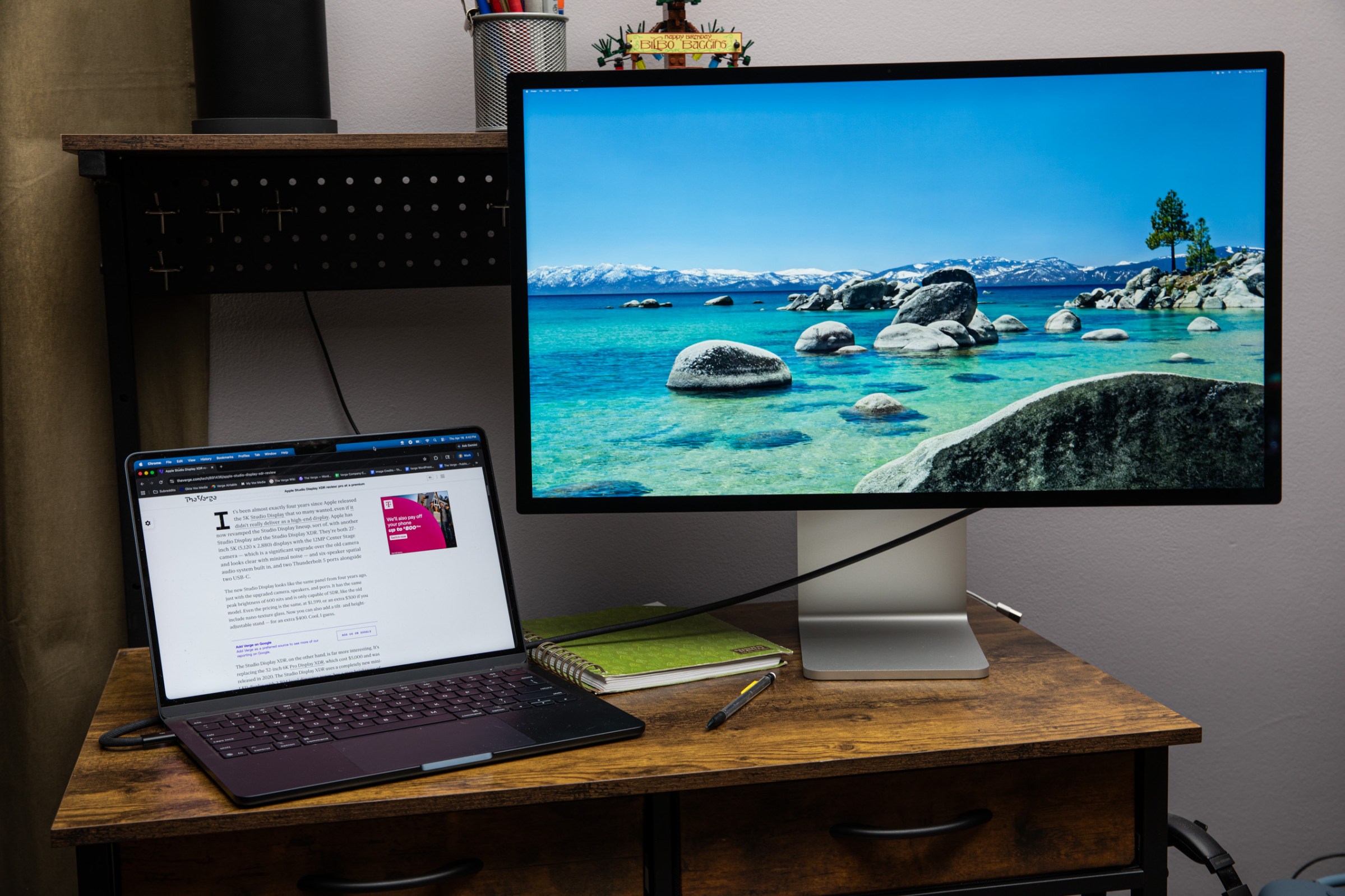 The Apple Studio Display on a small wooden desk with a MacBook Air next to it.