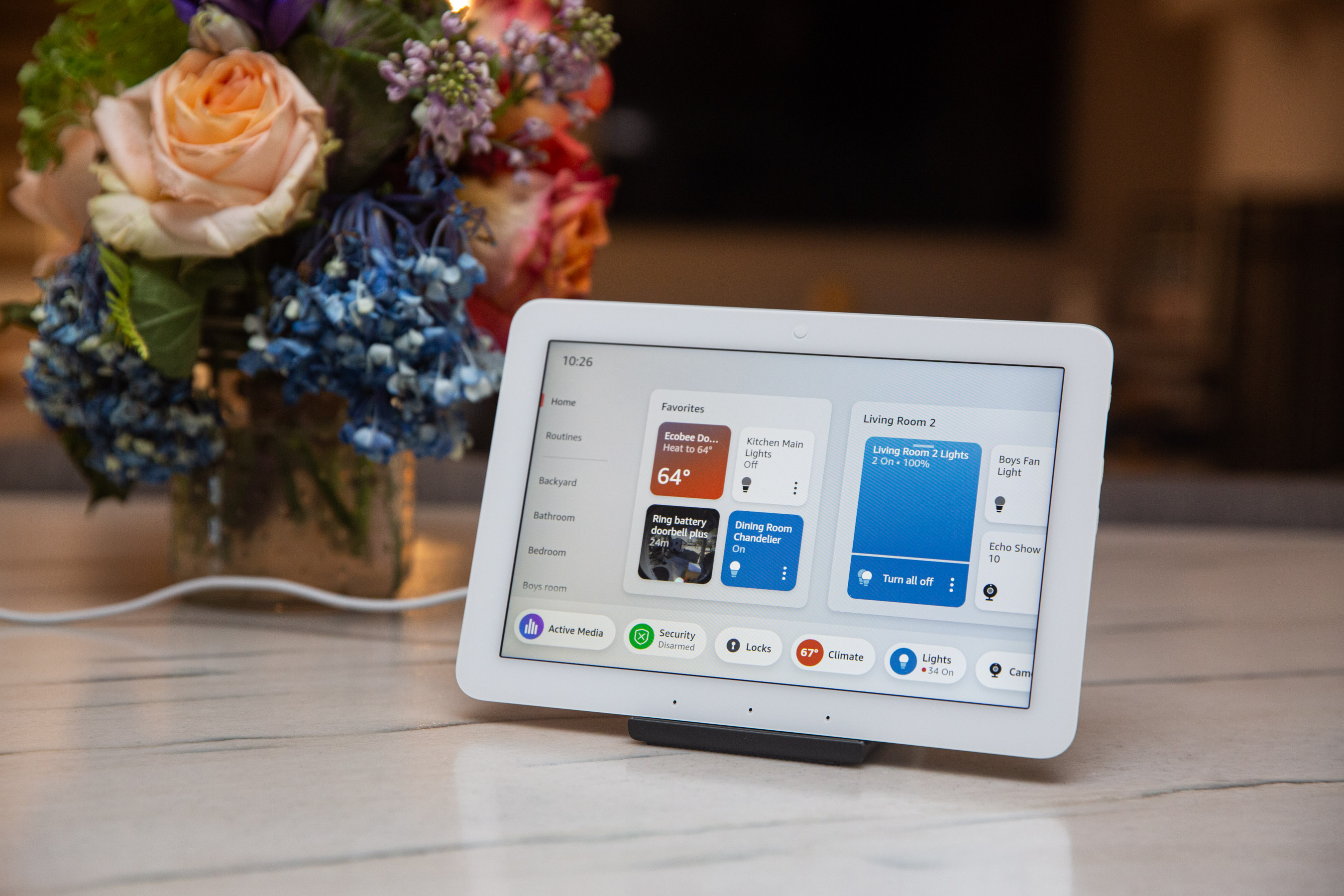 A small touchscreen tablet on a counter next to some flowers. A small touchscreen tablet on a counter next to some flowers.