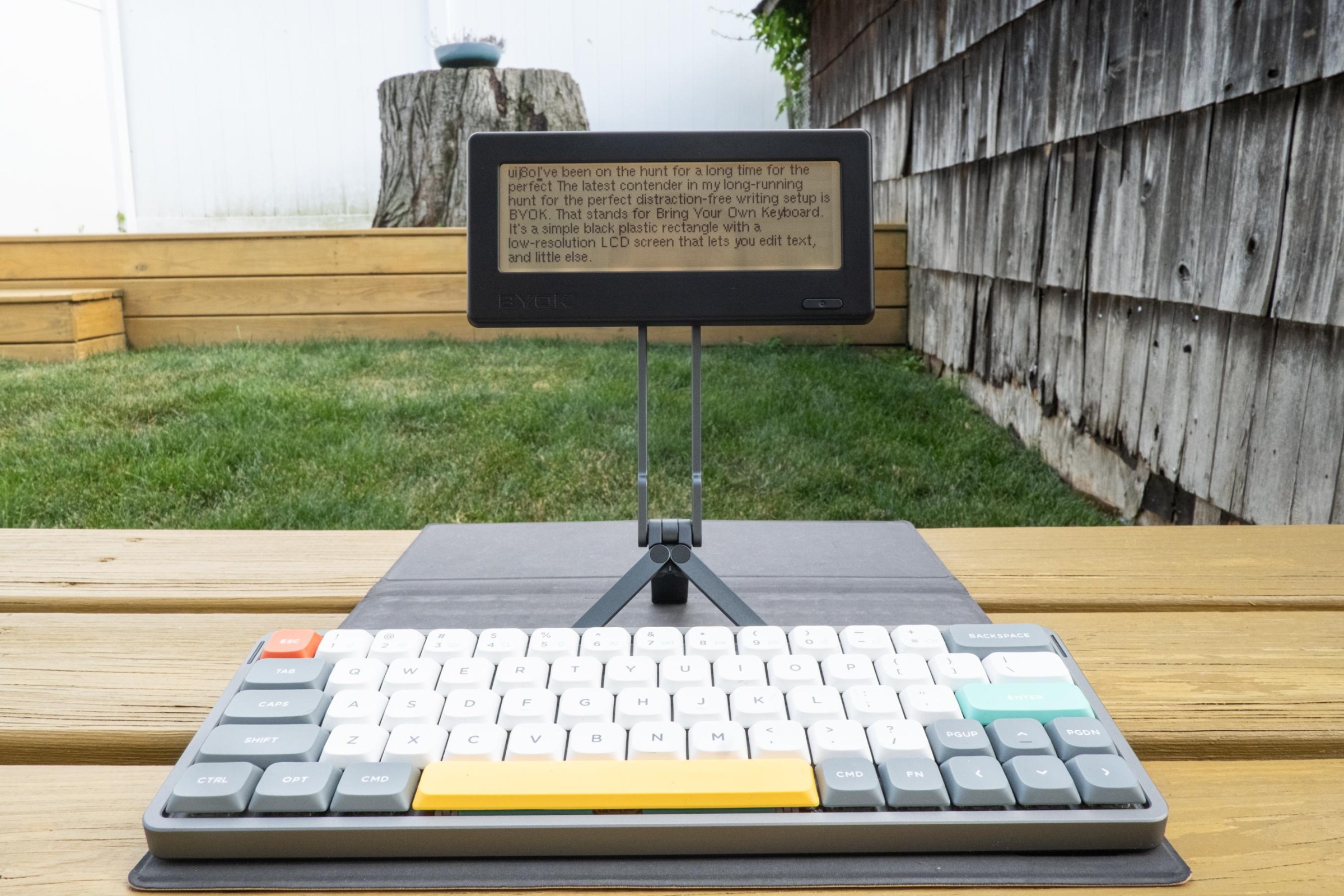 The BYOK on a tripod MagSafe stand paired with a NuPhy Air 60 keyboard in a backyard.