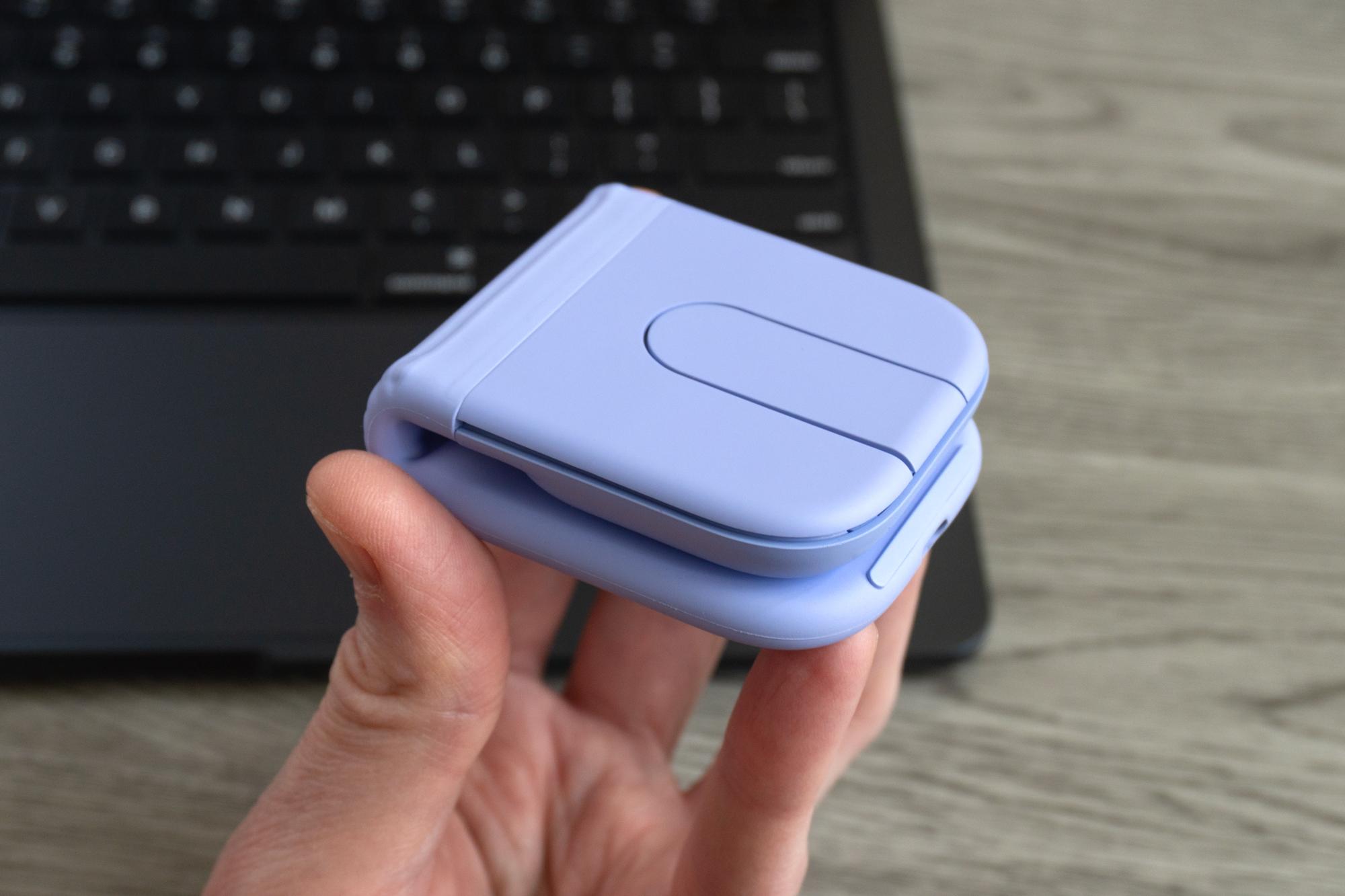 A person holds the Logitech Mobi Fold mouse in one handed while it’s folded in half.