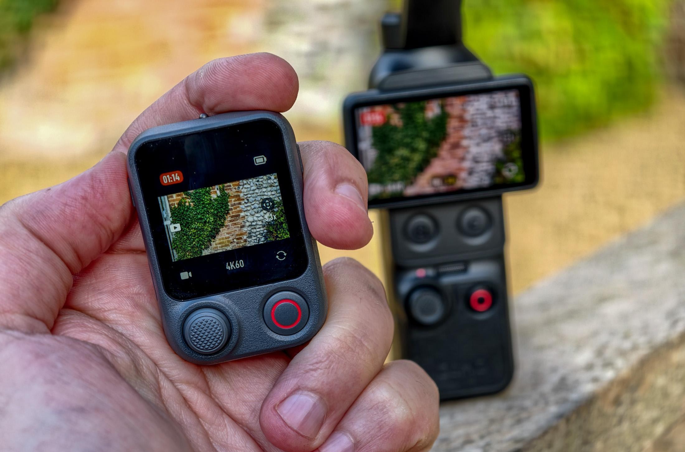 Photo of DJI Osmo Pocket 4P sitting on a wooden surface, with the FrameTap remote in the foreground showing that it is recording footage of a brick wall.
