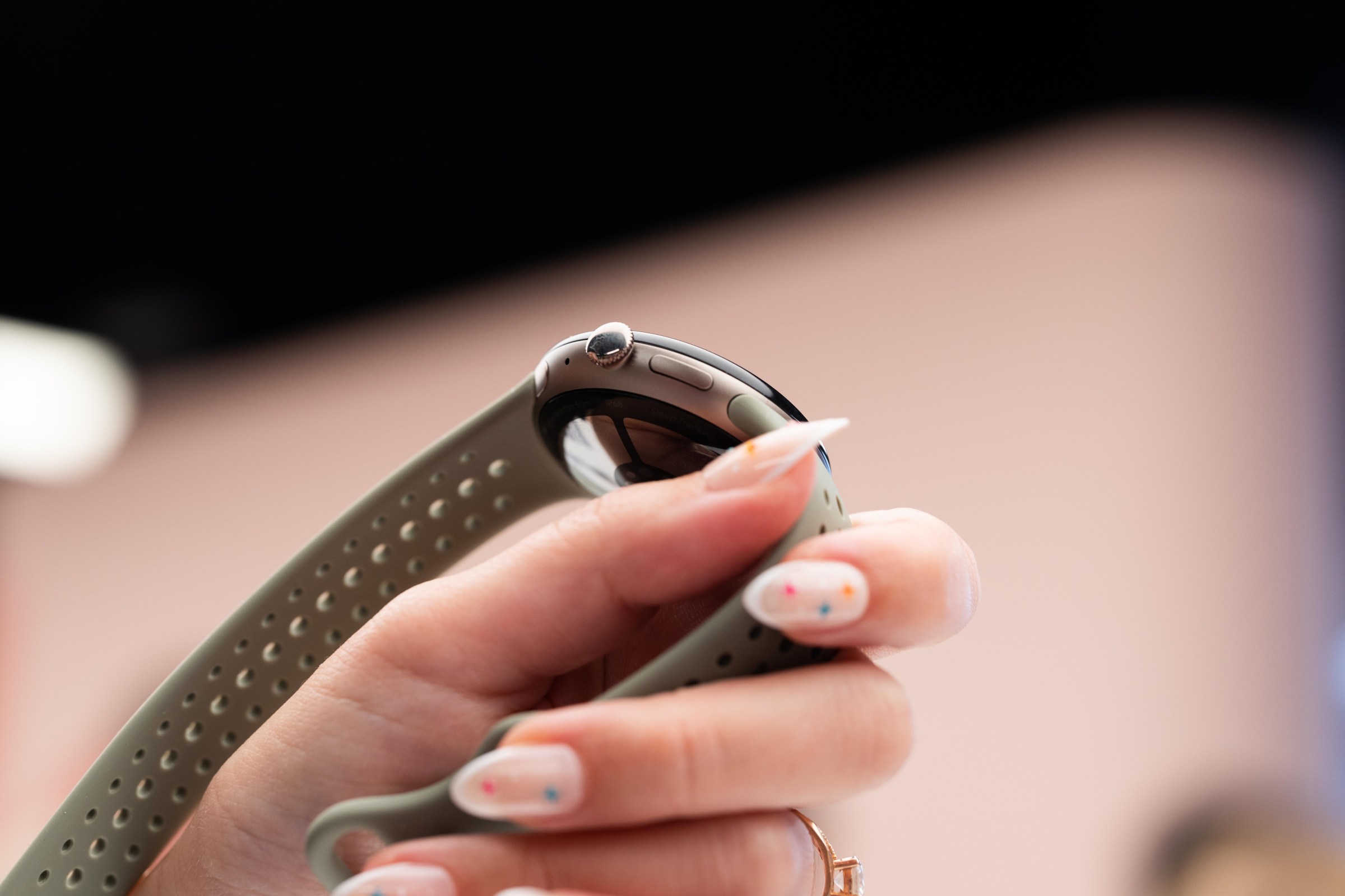Close up of the satin pyrite finish on the PIxel watch 5 and an olive color strap.