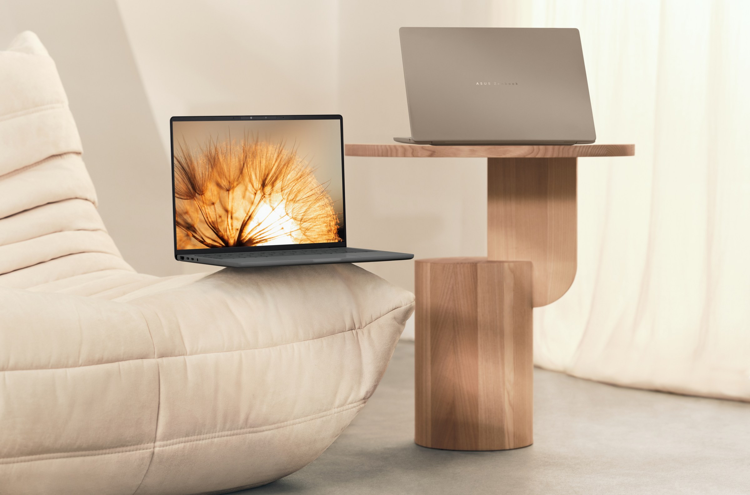 A pair of Asus Zenbook A14 laptops on a couch and end table.