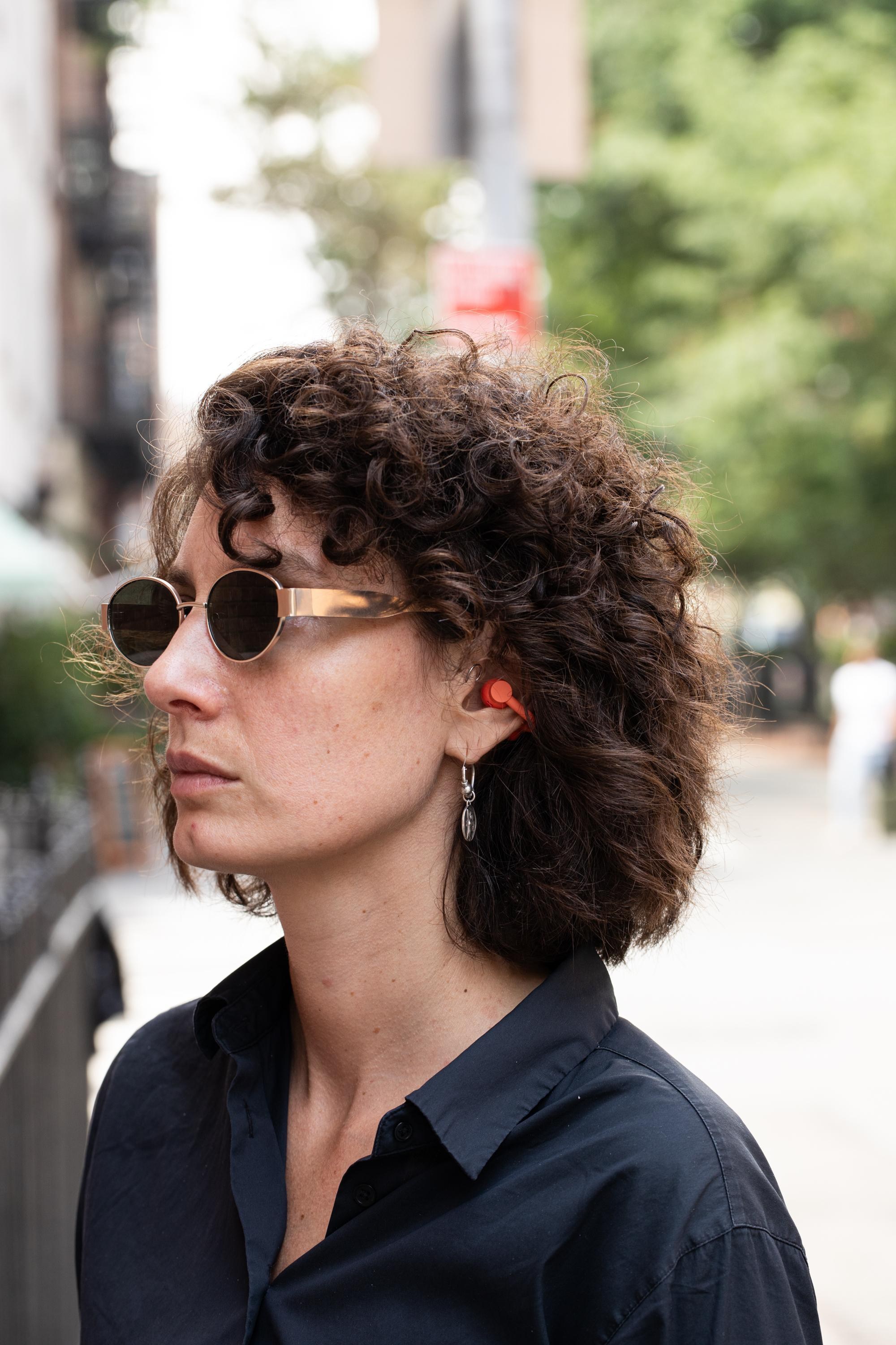 A person on a city street wearing the coral-colored CMF Clip Pro.