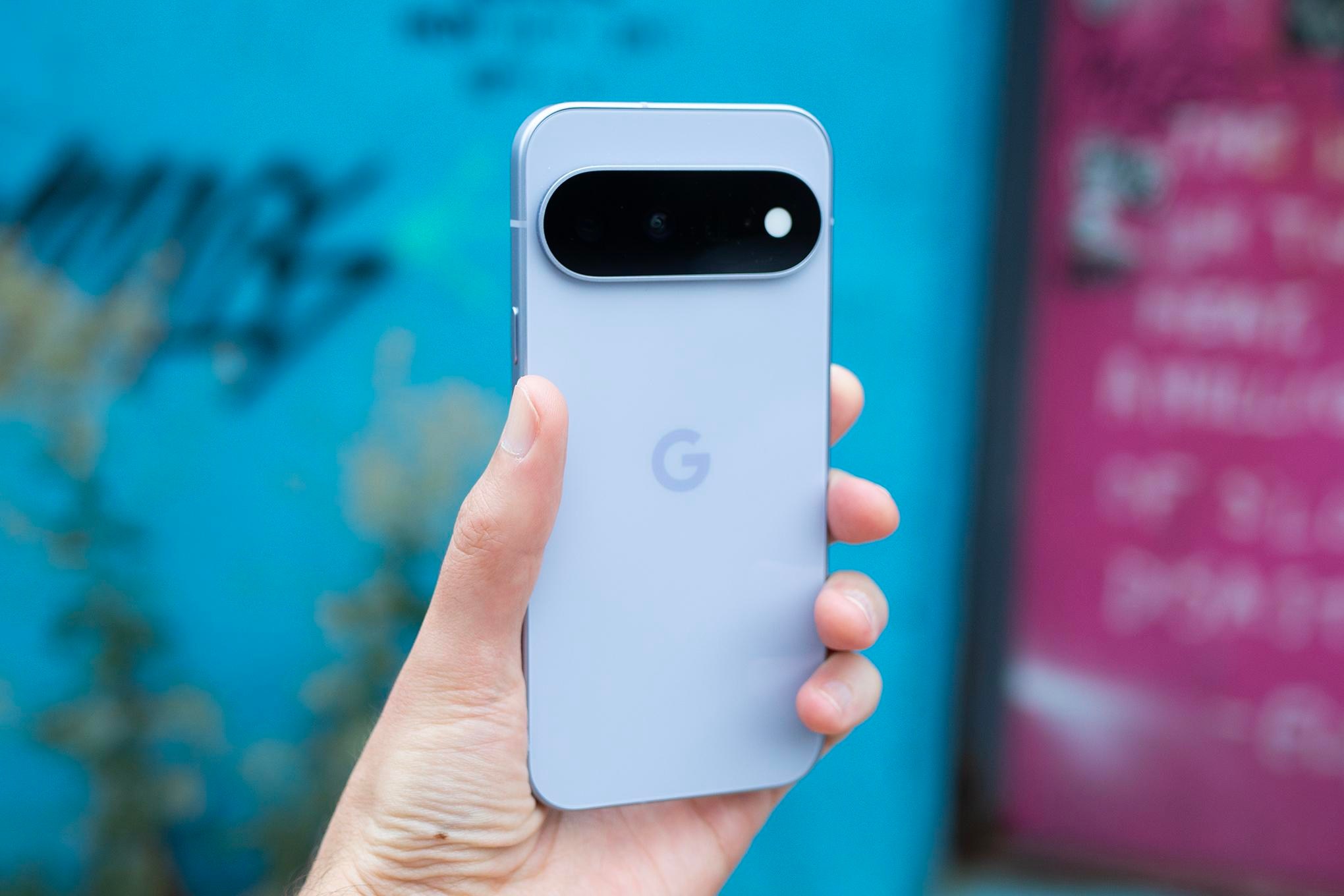 Google Pixel 11 in front of brightly colored blurry background.