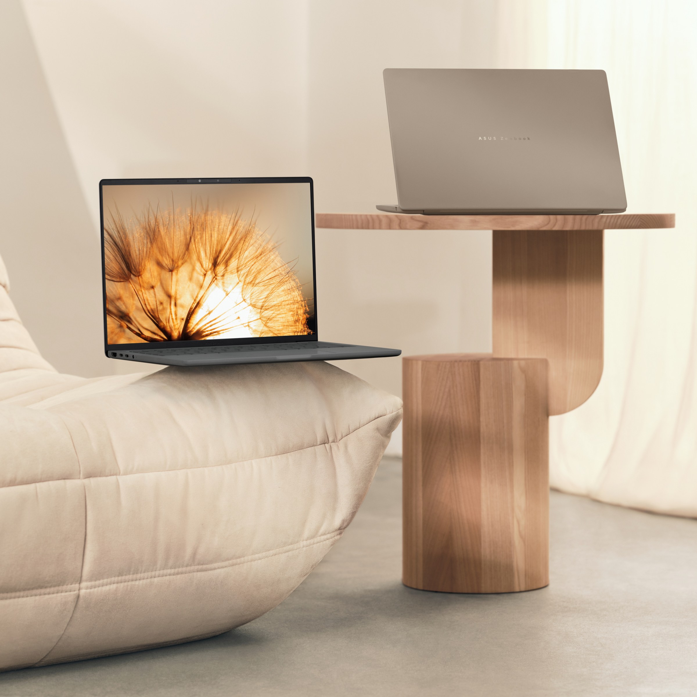 A pair of Asus Zenbook A14 laptops on a couch and end table.