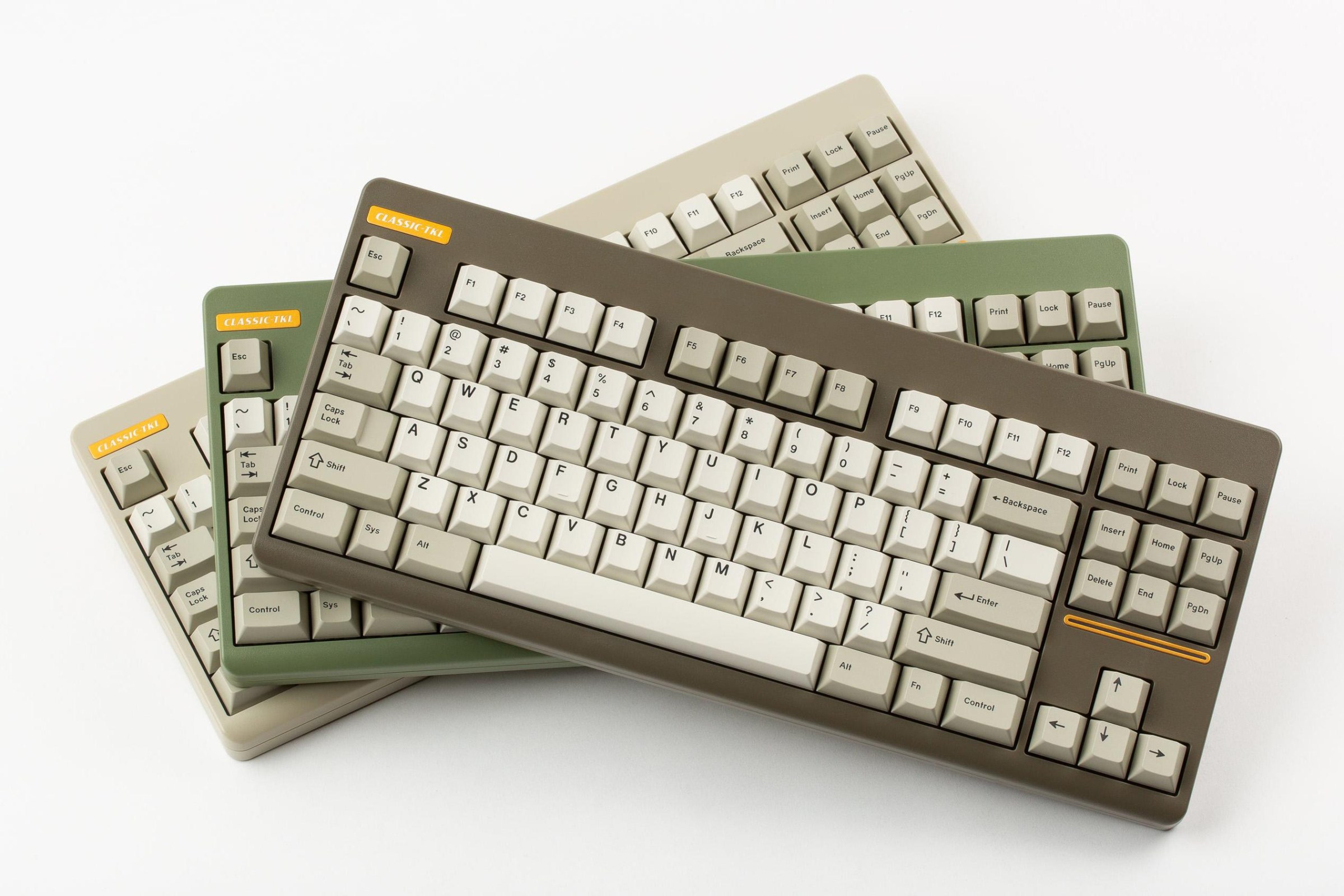 three classic keyboards with beige keycaps. the top one is taupe, the middle is a dusty green, and the bottom is warm beige