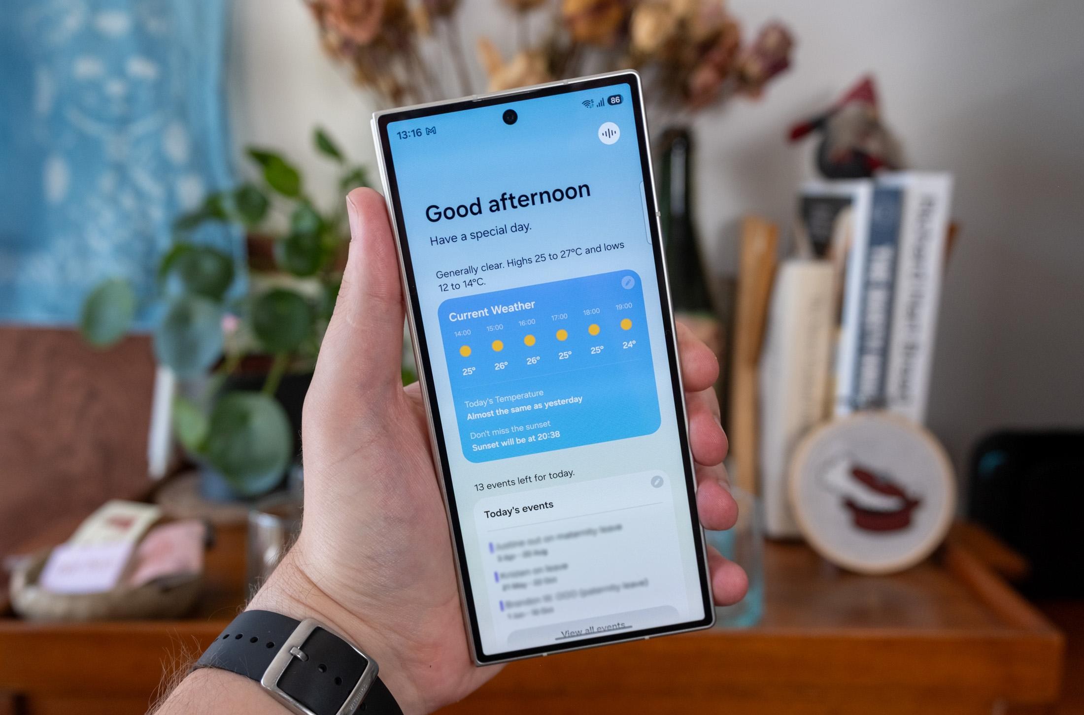 Photo of Samsung Galaxy Z Fold 8 Ultra in a hand in front of a bookcase, showing the Now Brief on the outer display