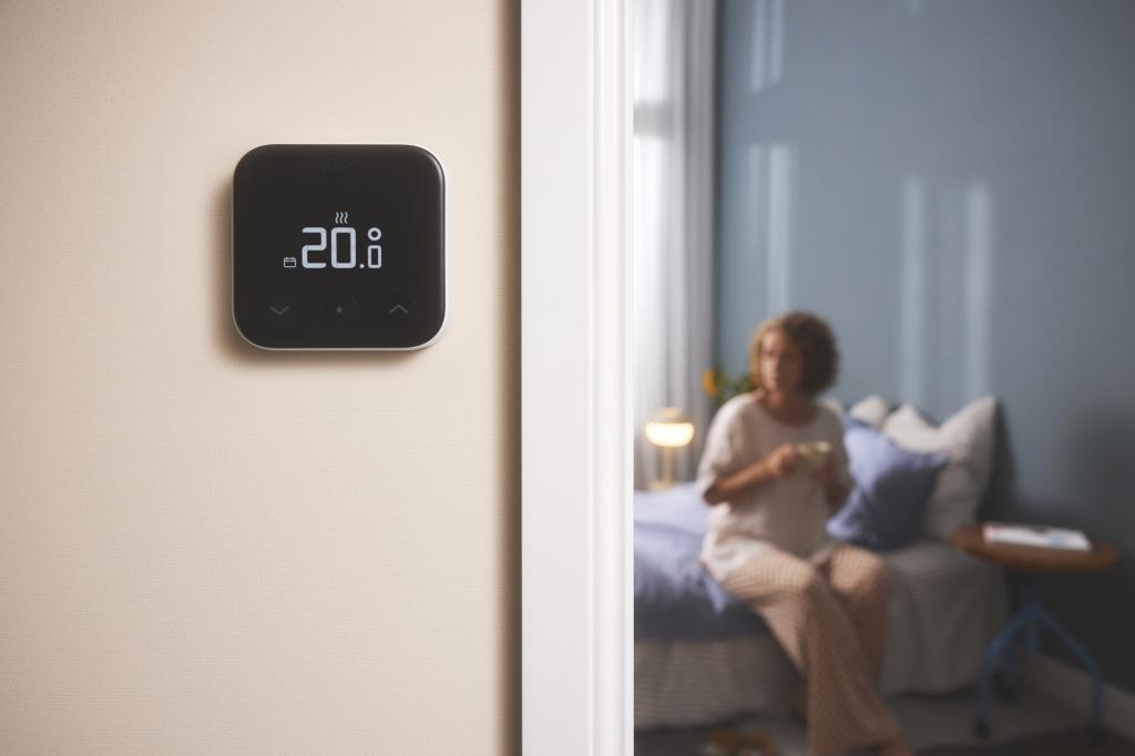 Tado X Thermostat on a wall with a woman in the room