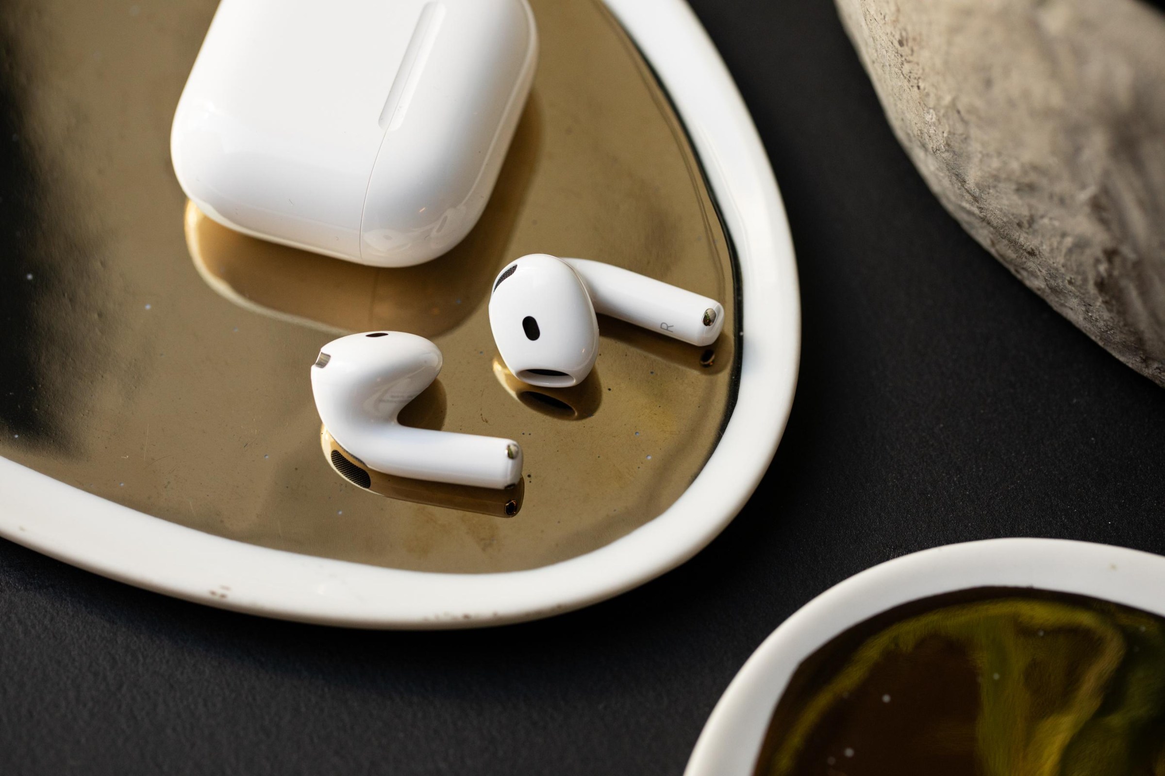 The AirPods 5 next to their wireless charging case.
