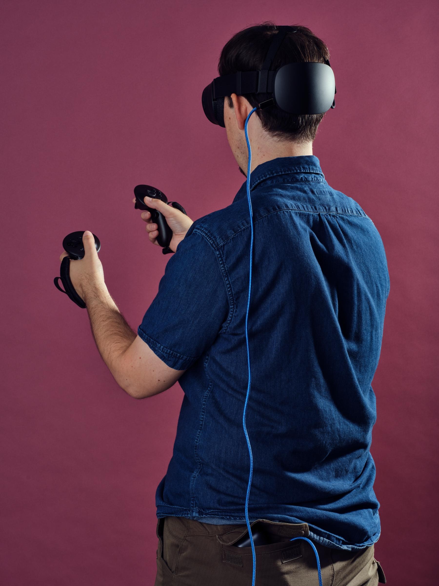 A blue USB-C cable leads from the Steam Frame’s port down to Sean’s back pocket where a battery is attached.